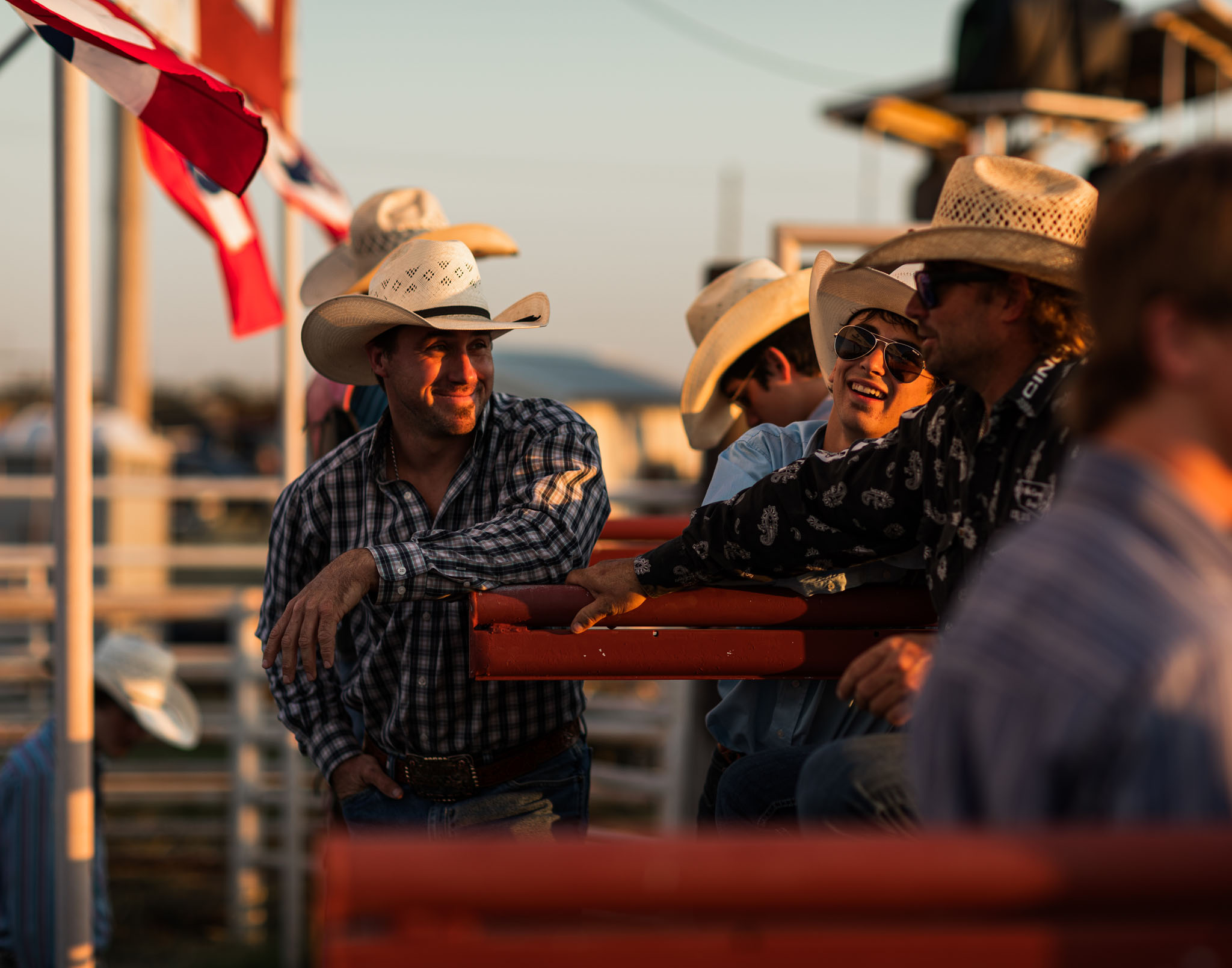 Cowboys laughing together behind the chutes