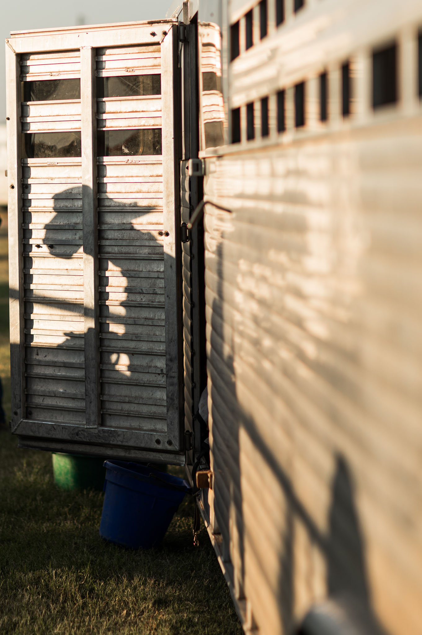 Shadow of a cowboy falling across a livestock trailer