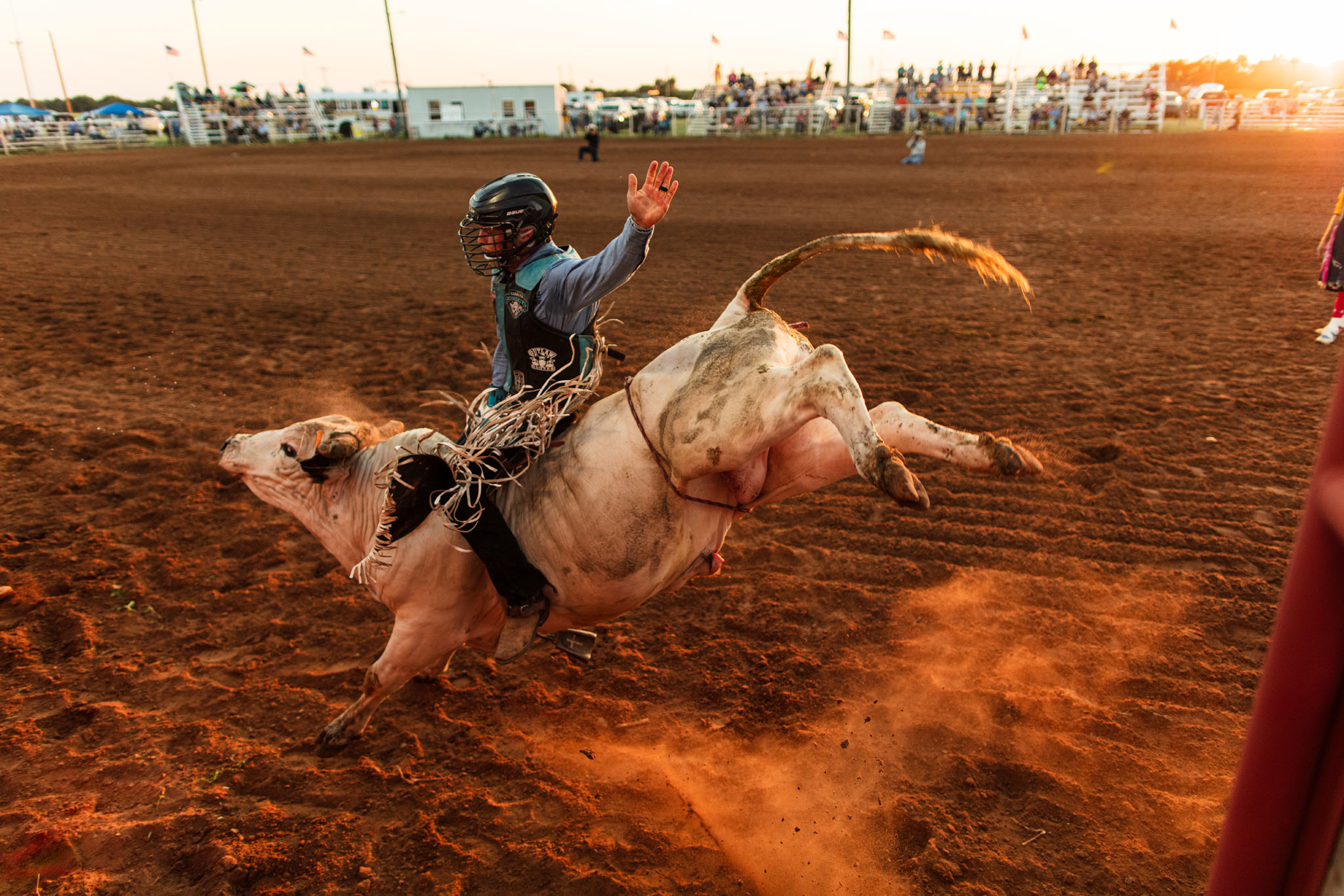 Bull rider holding on as the bull kicks up dirt