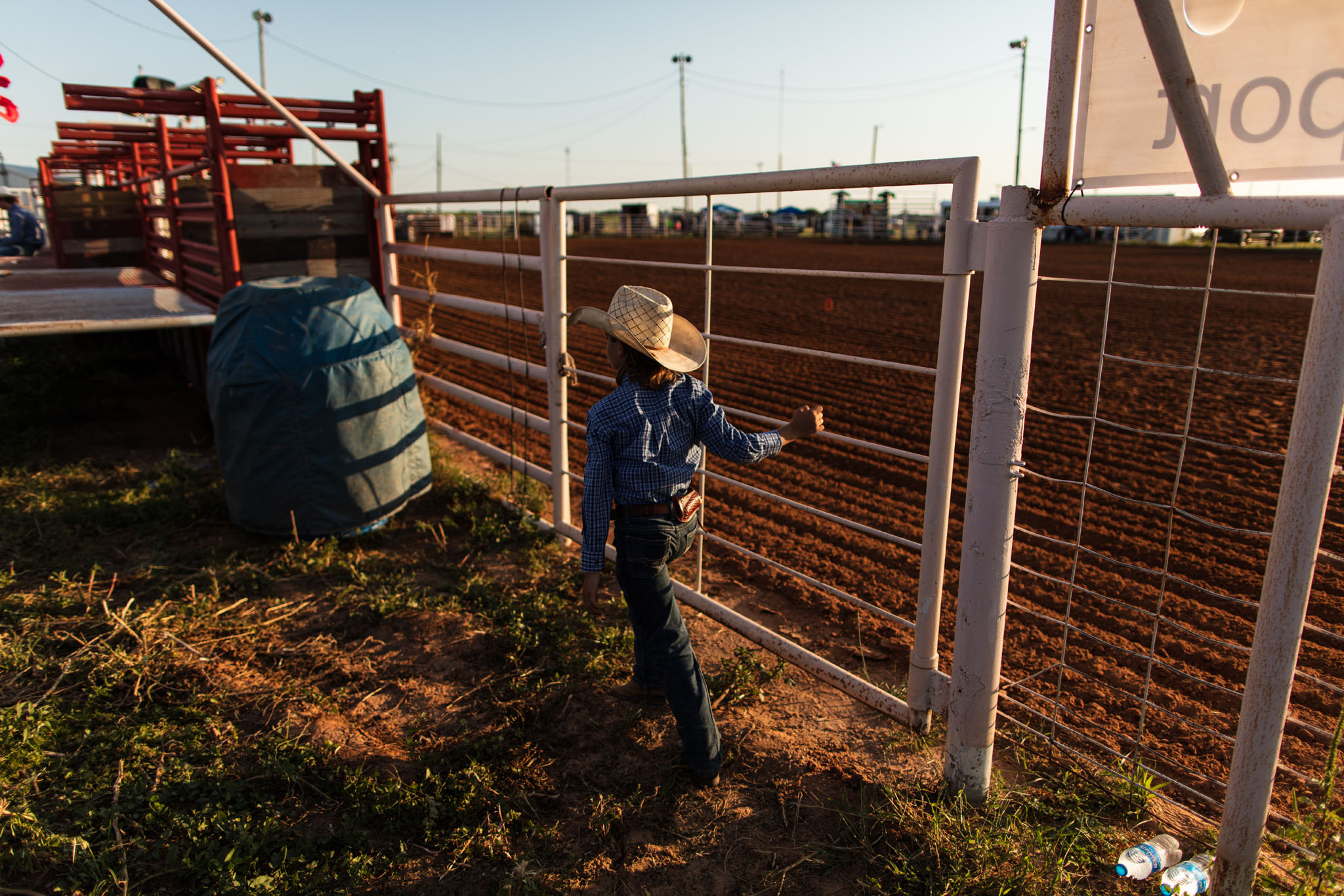 Young cowboy walking along the pens