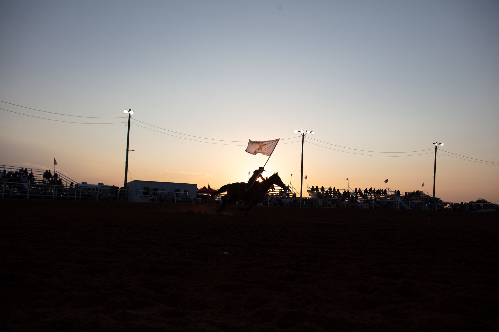 Flag rider silhouetted across the arena at dusk