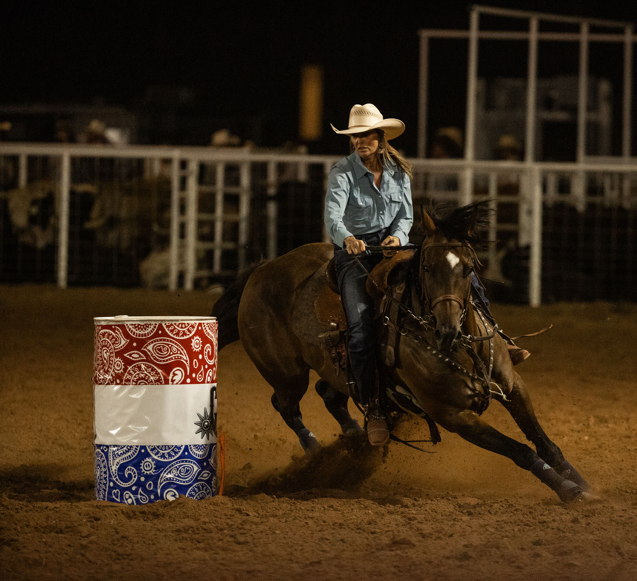 Barrel racer turning a barrel under the arena lights