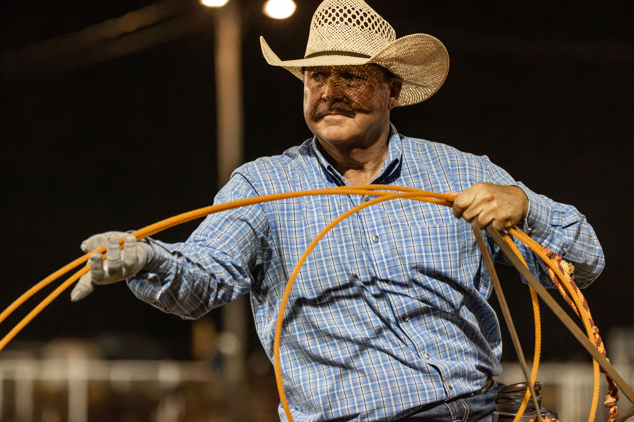 Roper coiling his rope under the arena lights
