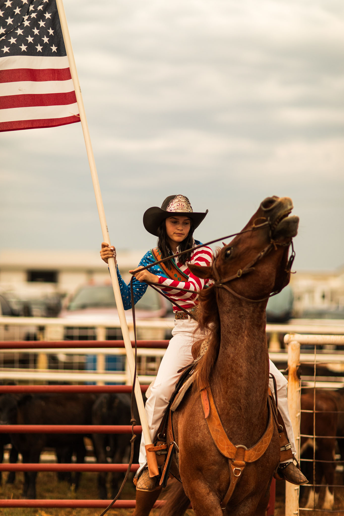 Young cowgirl carrying the American flag on horseback
