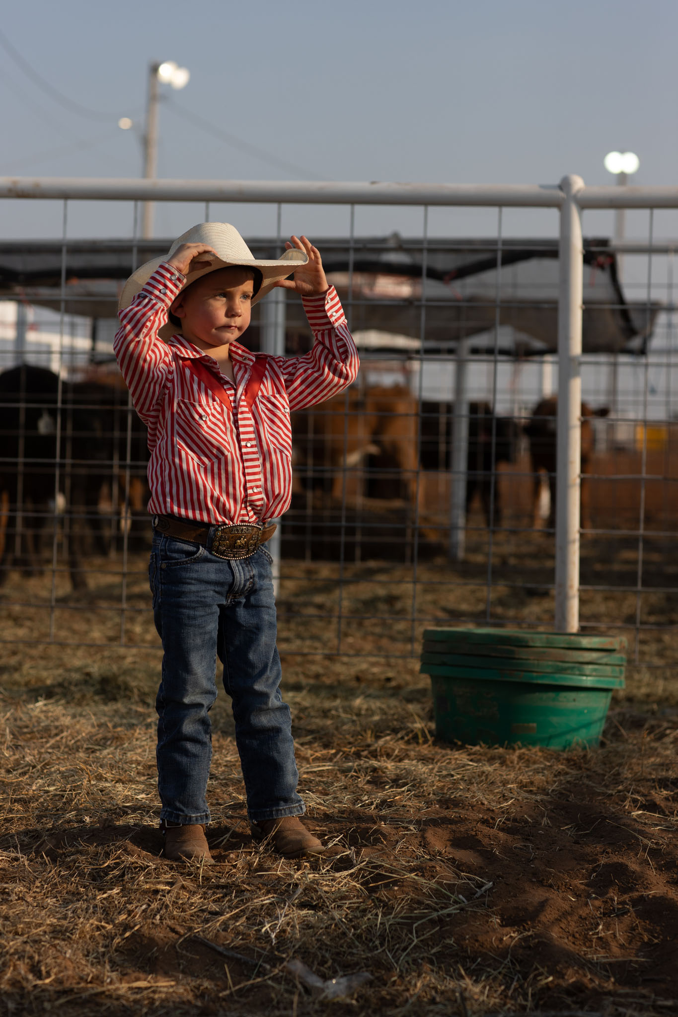 Boy in a pink shirt tipping his hat in the arena
