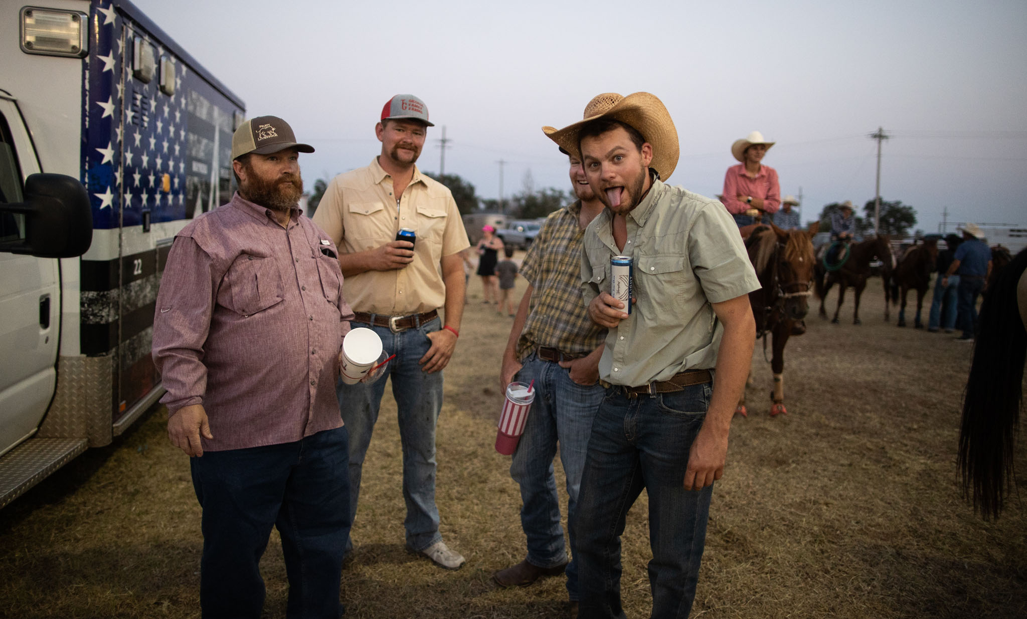 Cowboys standing together near the arena at dusk
