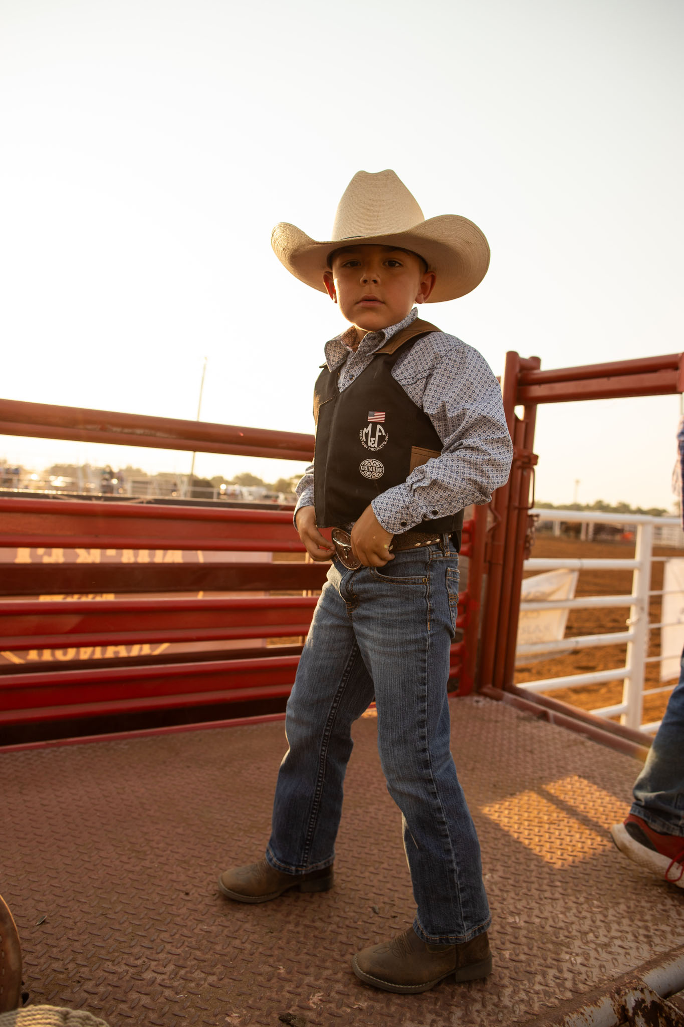 Young boy in a cowboy hat standing on a platform by the chutes