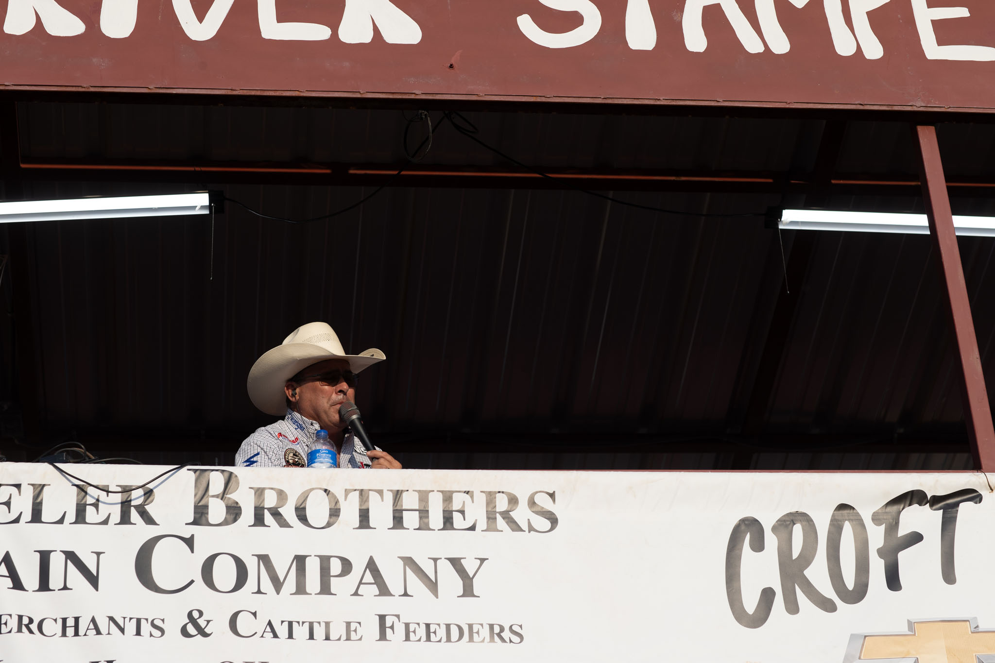 Announcer seated beneath the Cimarron River Stampede sign