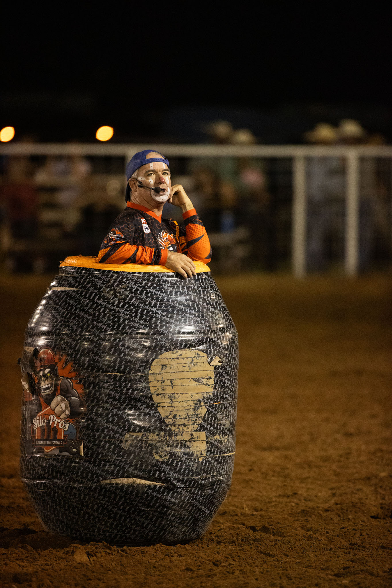 Rodeo clown peeking out of a barrel in the arena