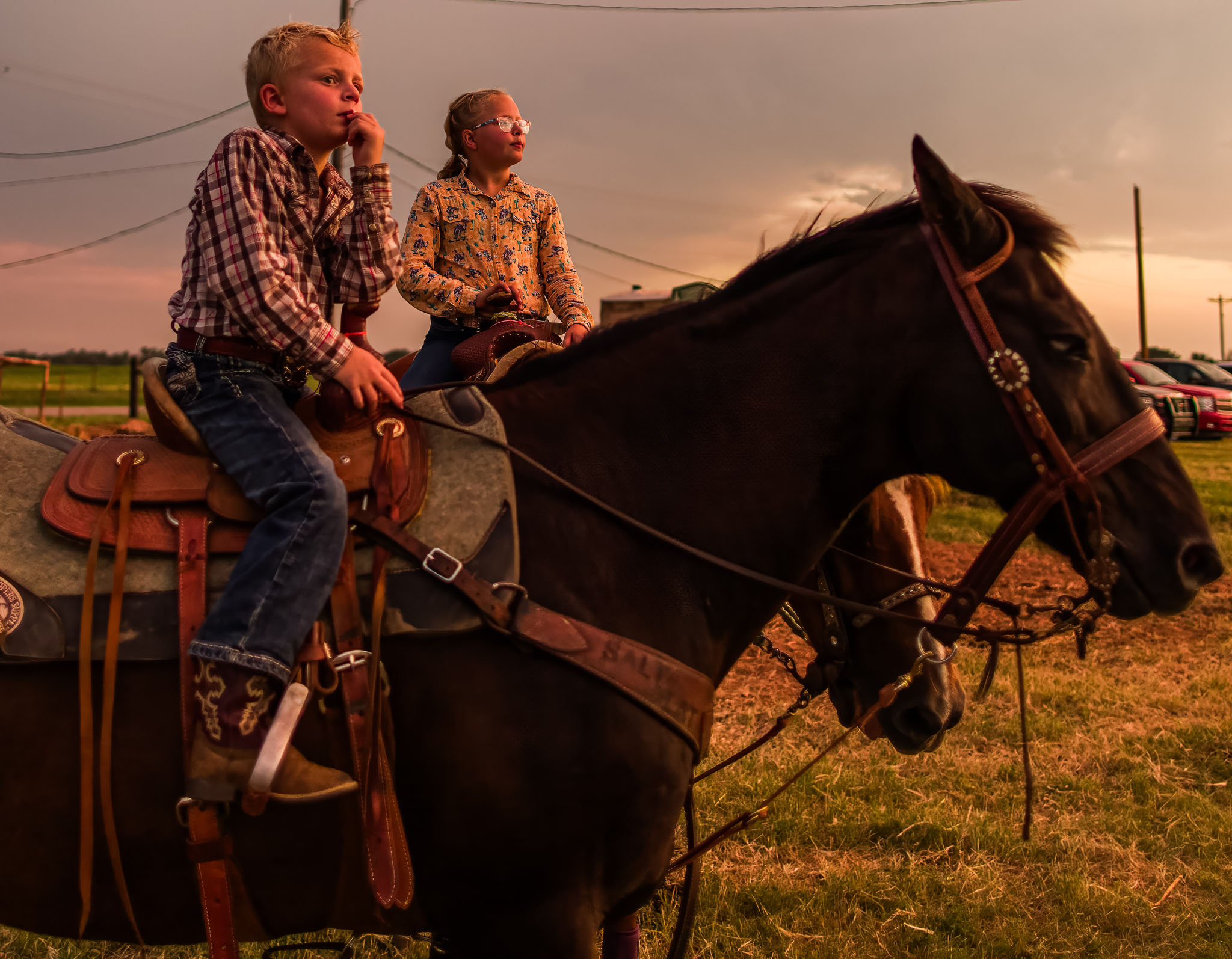 Two children sitting on a horse at dusk