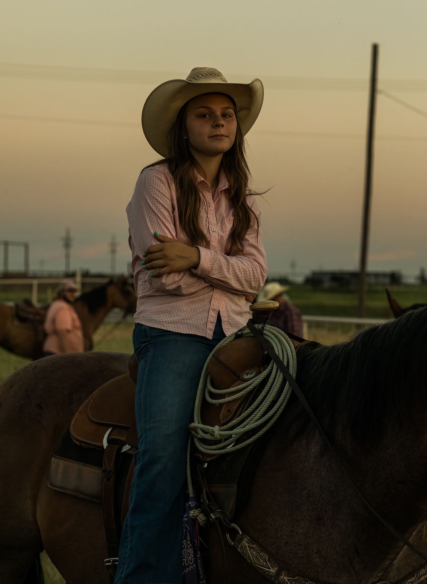 Young cowgirl in a straw hat sitting on her horse with a rope