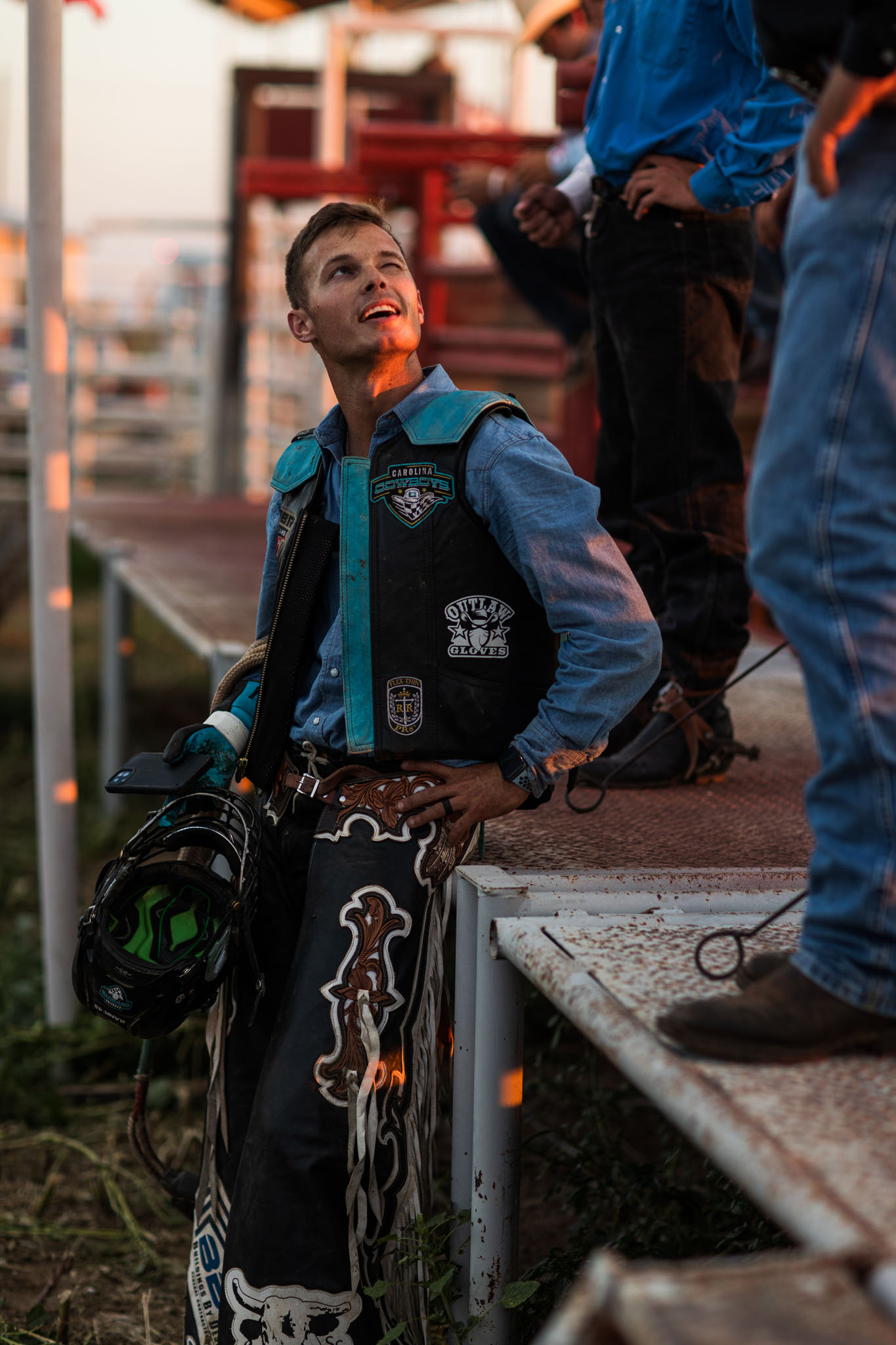 Bull rider in his vest and chaps waiting behind the chutes