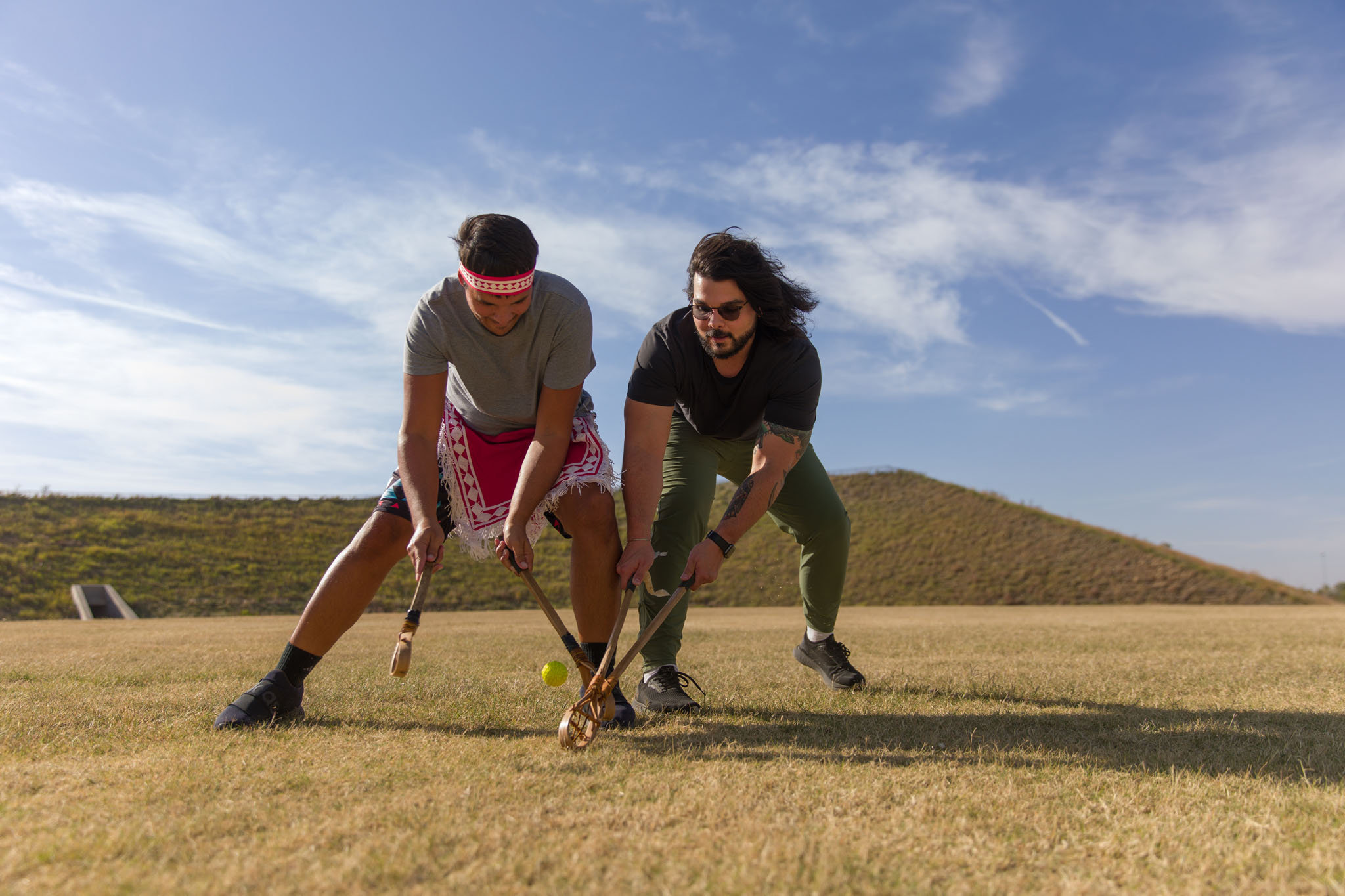 Two players reaching for the ball in a stickball game