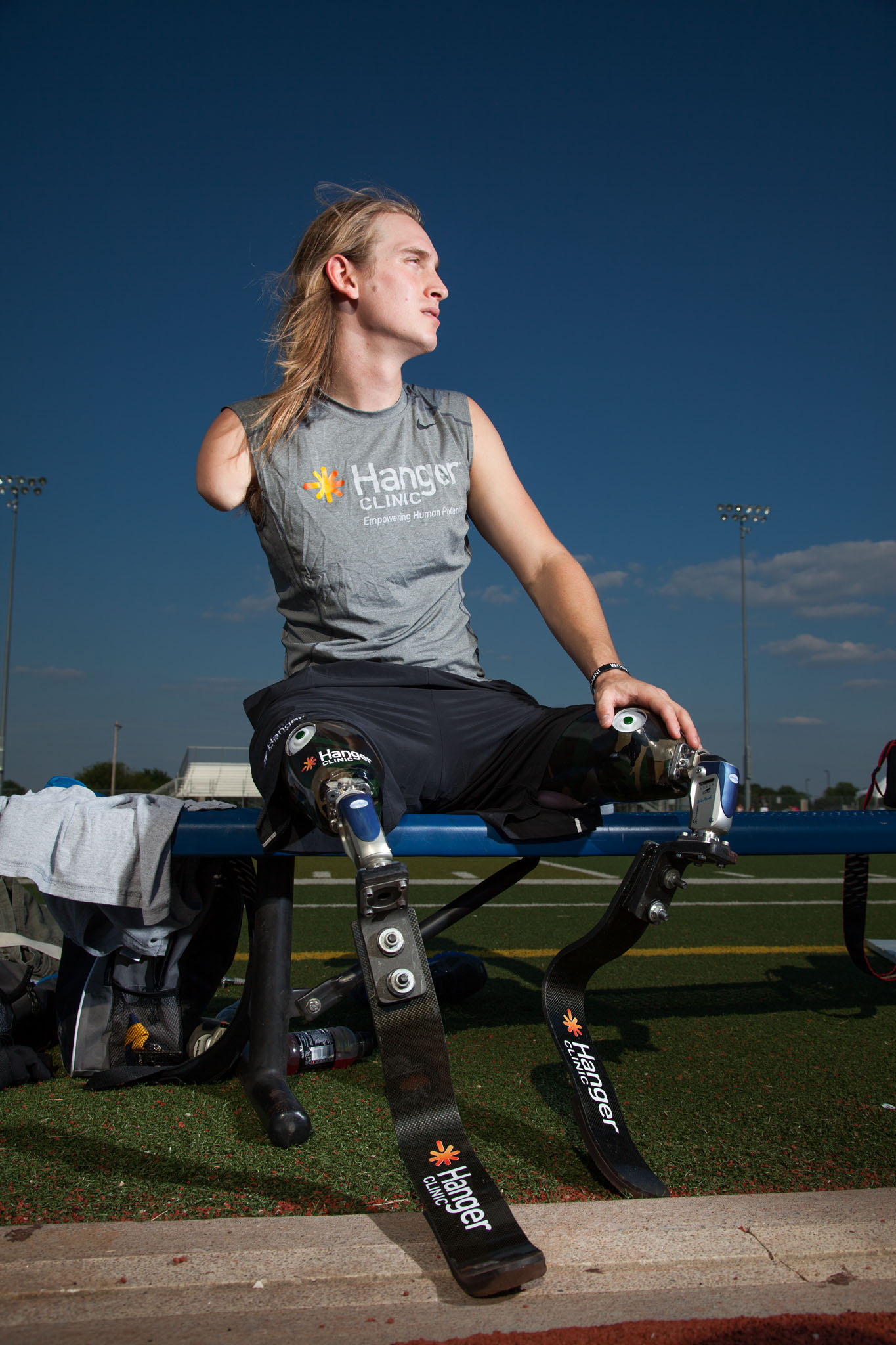 Athlete with running blades seated on the field at dusk