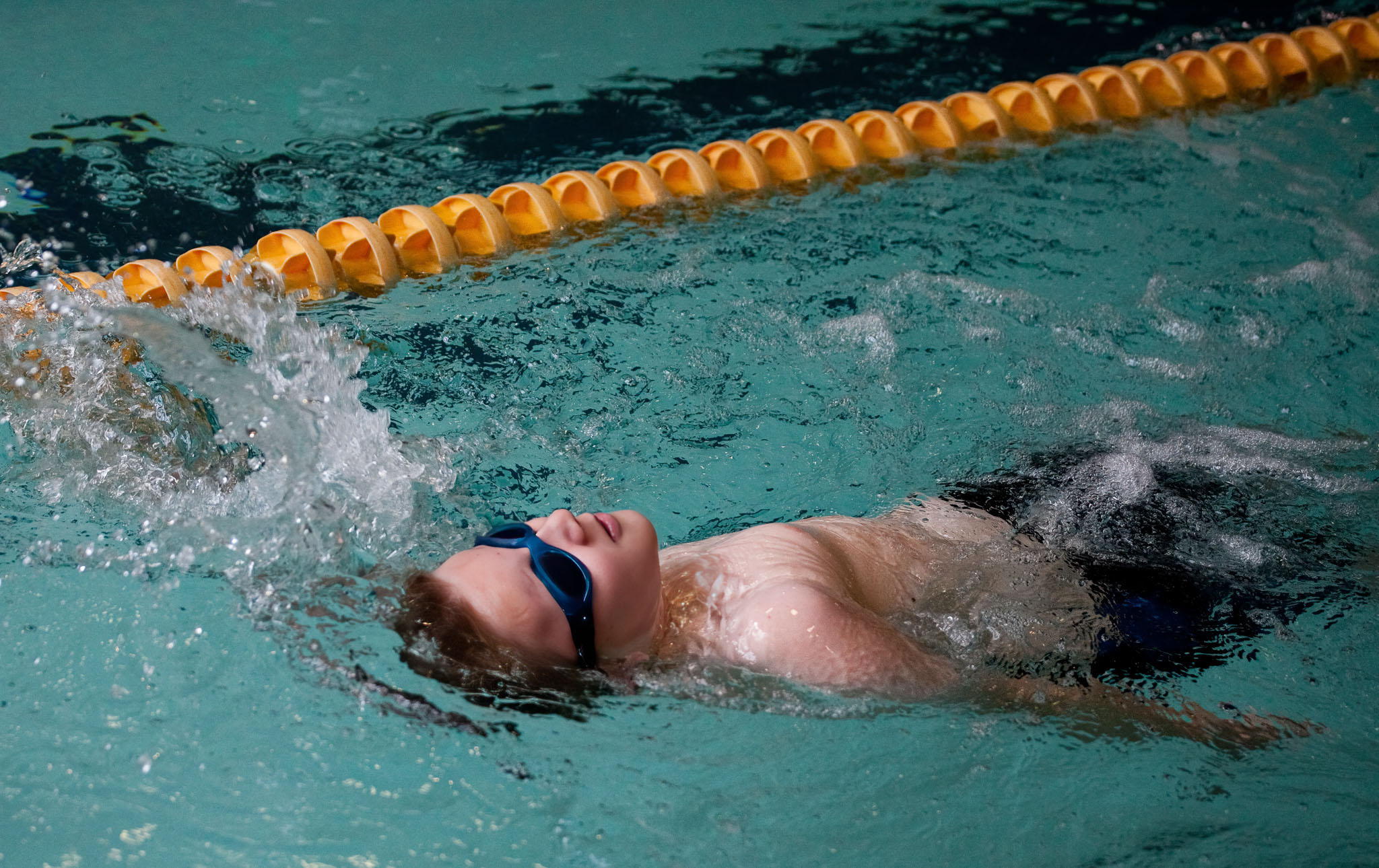 Swimmer doing the backstroke beside a lane line
