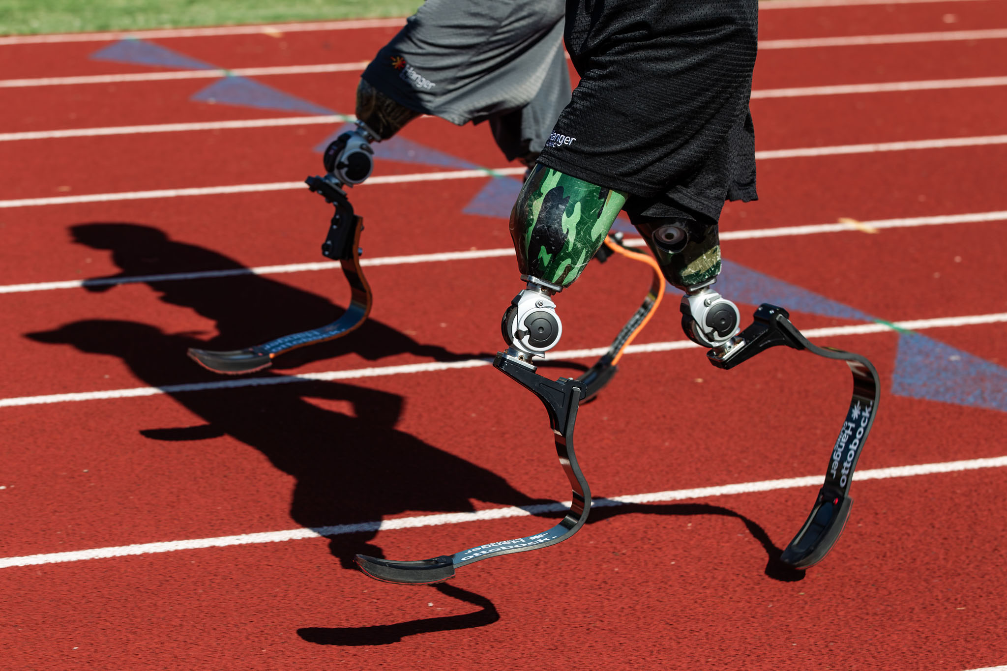 Shadows of running blades stretched across a red track