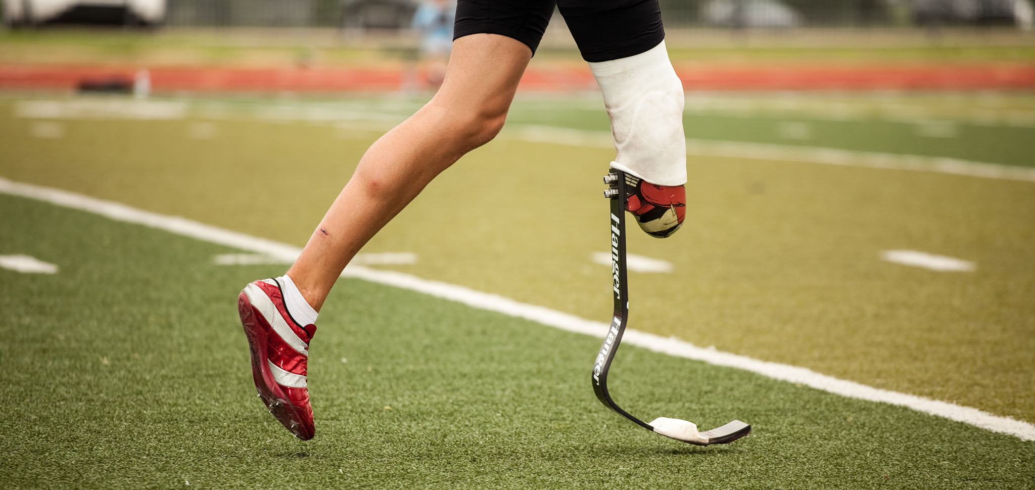 Runner’s prosthetic leg and blade mid-stride on the field