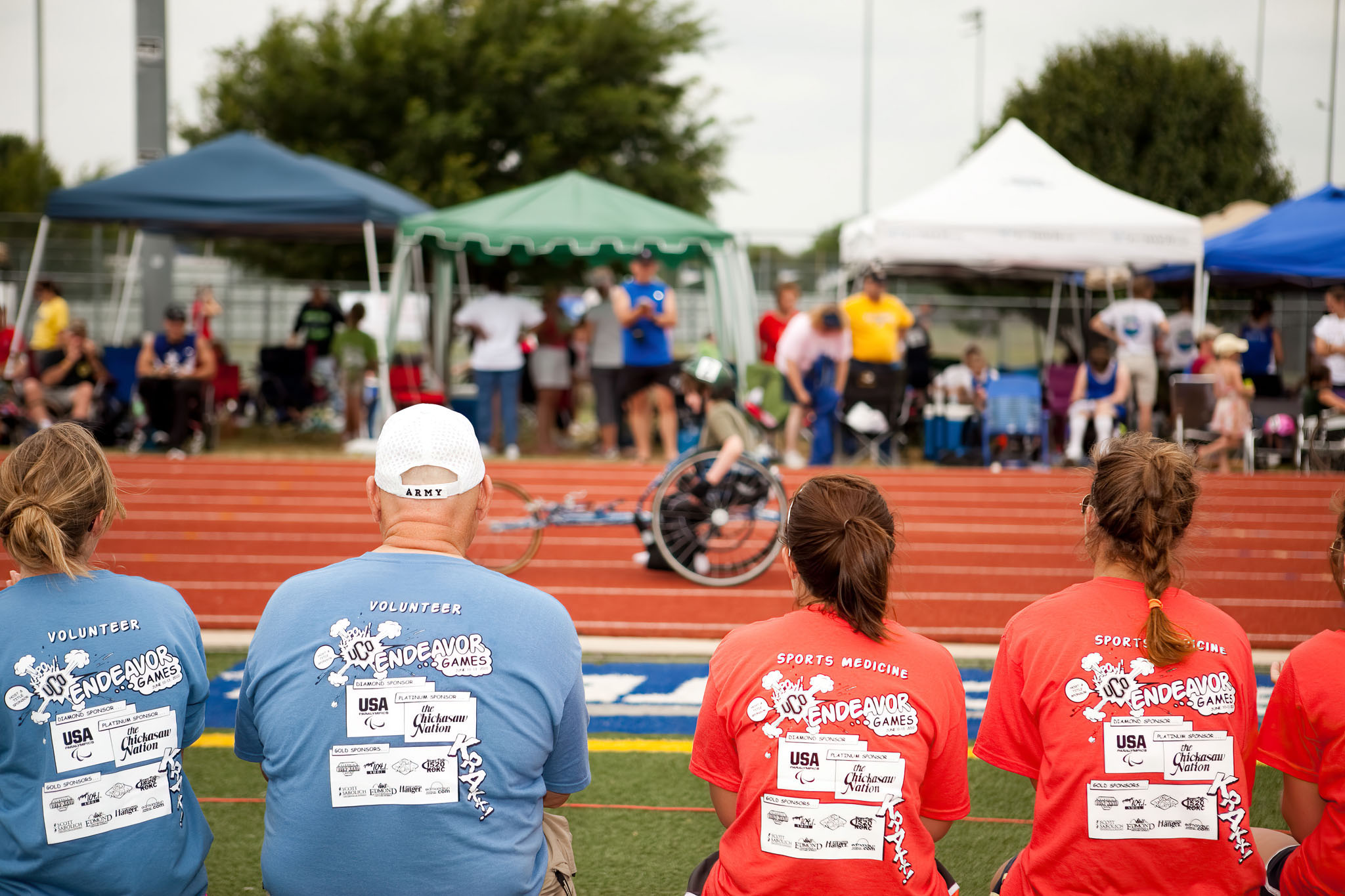 Volunteers in matching shirts watching an event beside the track