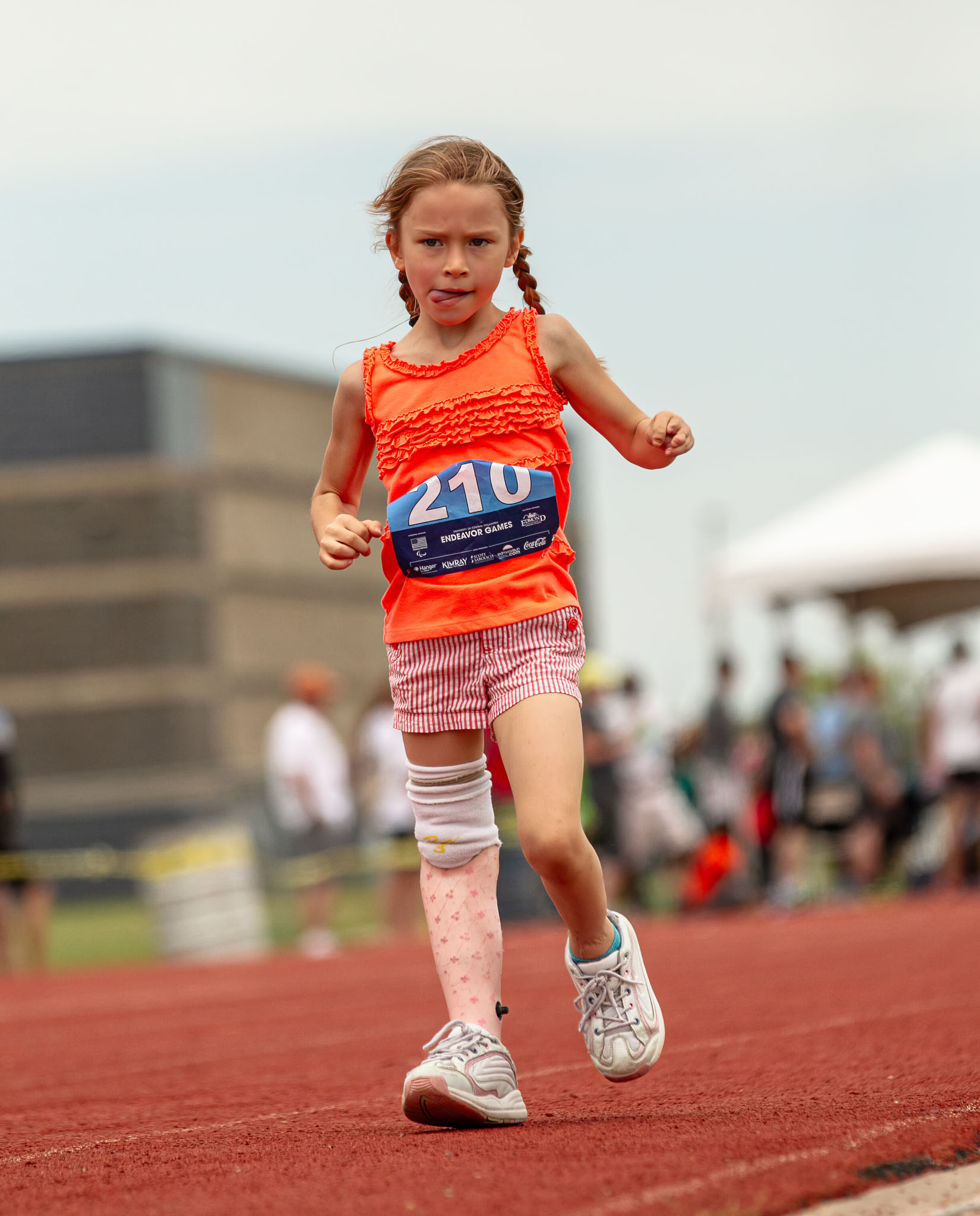 Girl in a race bib running on a prosthetic leg