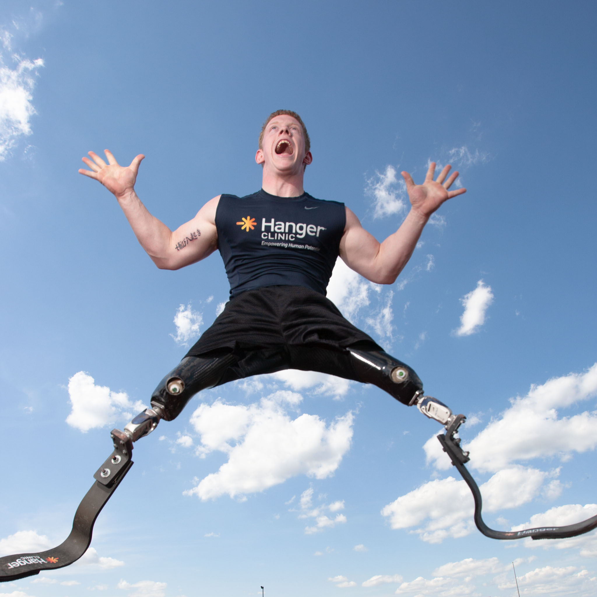 Athlete on running blades leaping against a blue sky with clouds