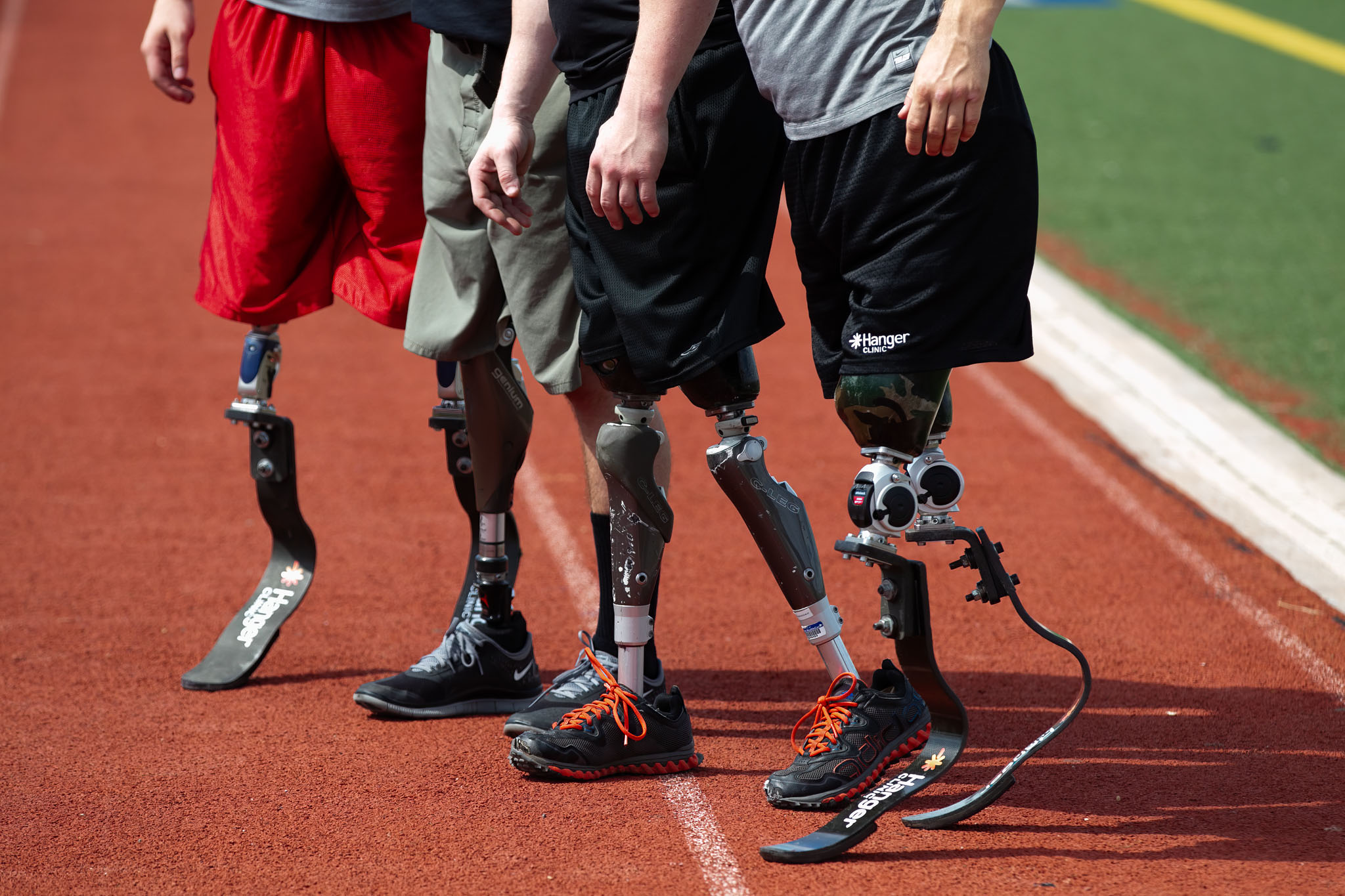 Athletes standing on prosthetic legs and running blades along the track