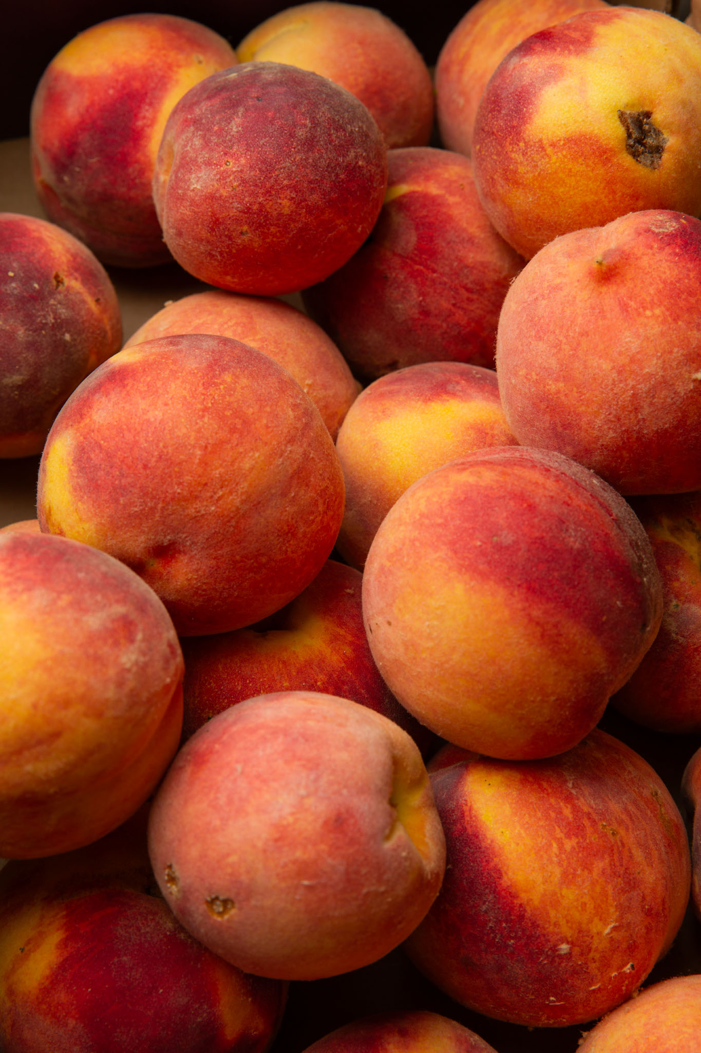 Ripe peaches with red and gold skin piled together