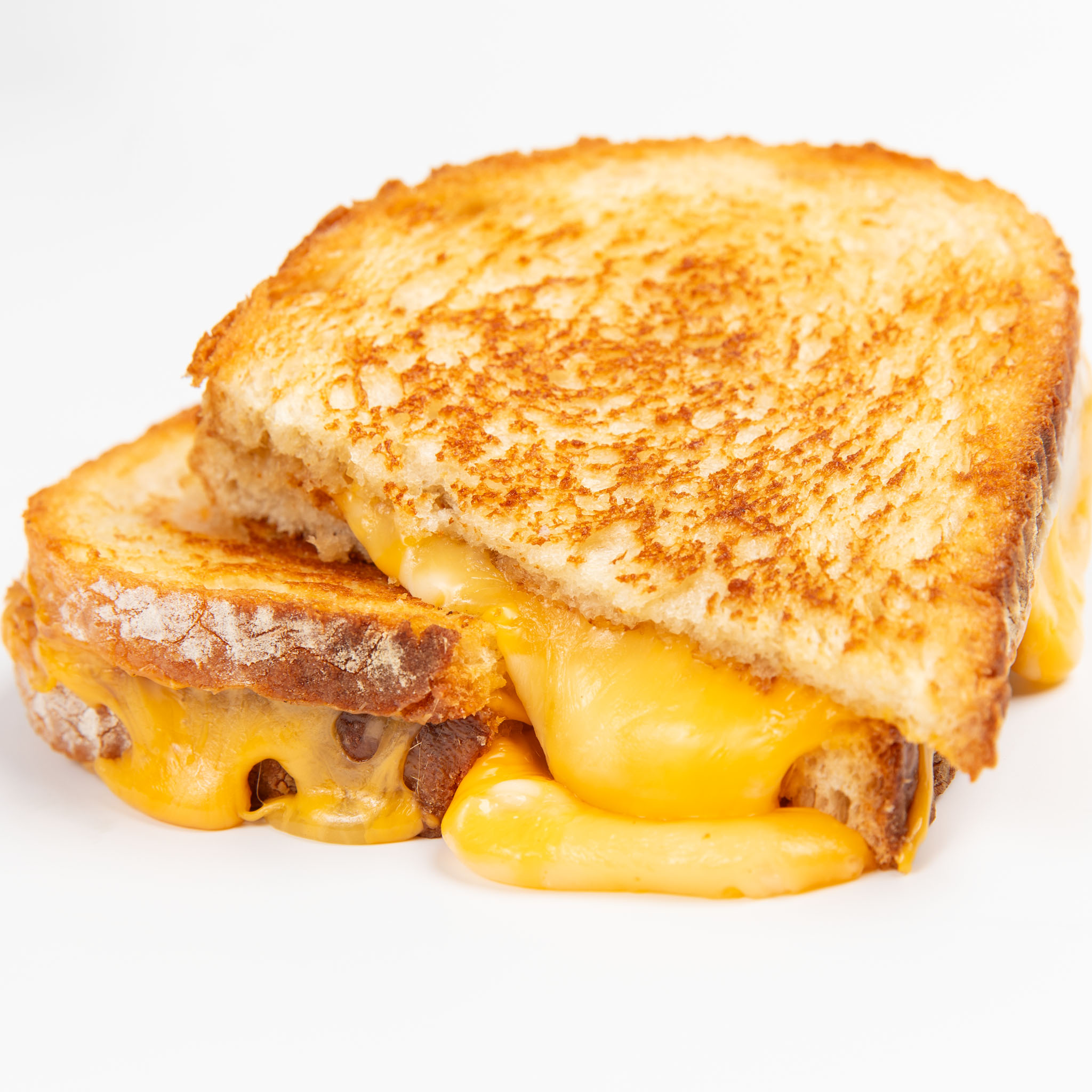 Golden grilled cheese sandwich with melted cheese oozing out, cut in half on a white background