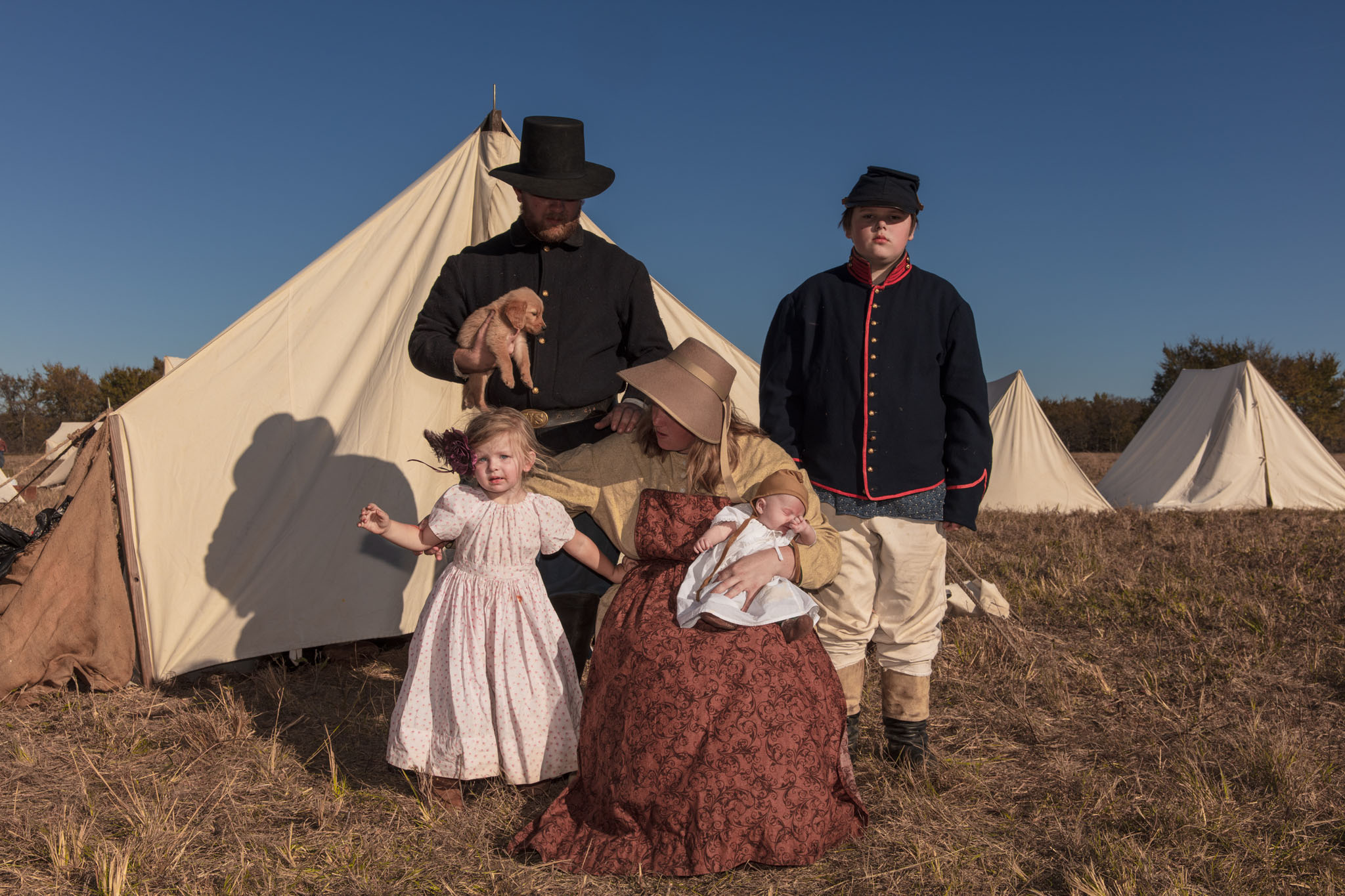 Family in period clothing posing in front of their tent