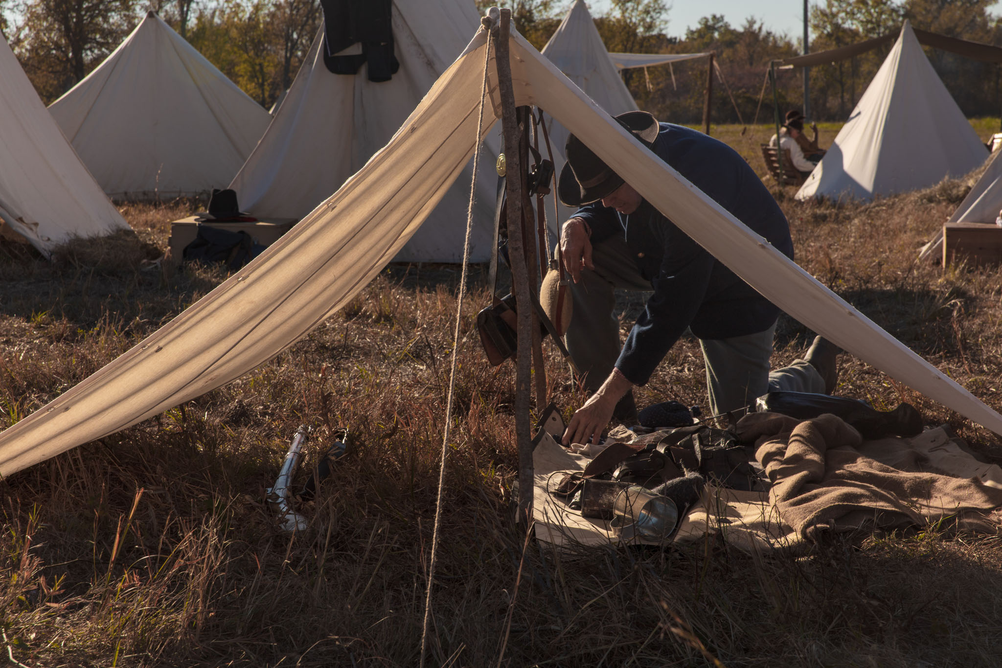 Reenactor working inside an open tent in camp