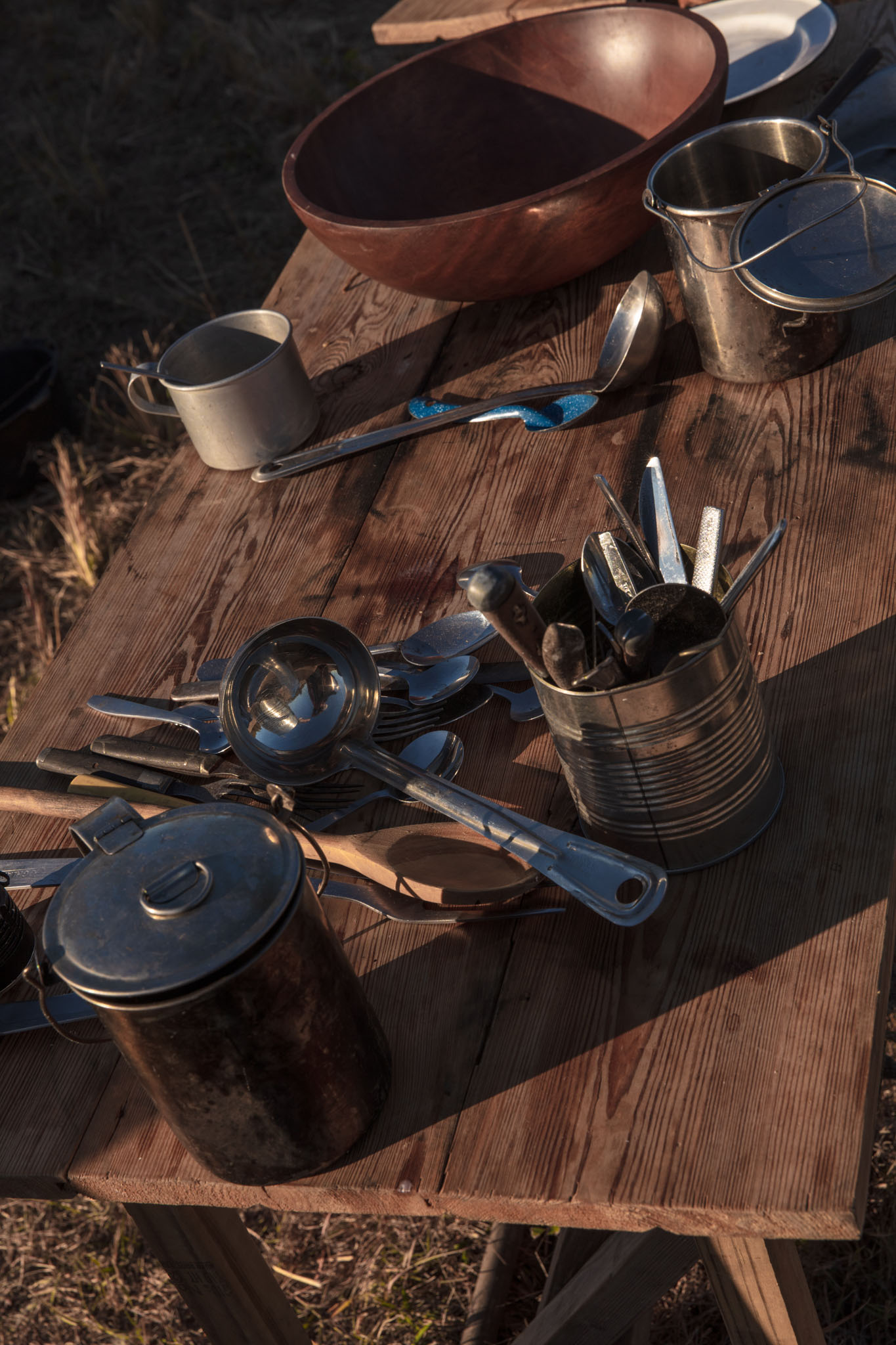 Tin cookware and utensils on a wooden camp table
