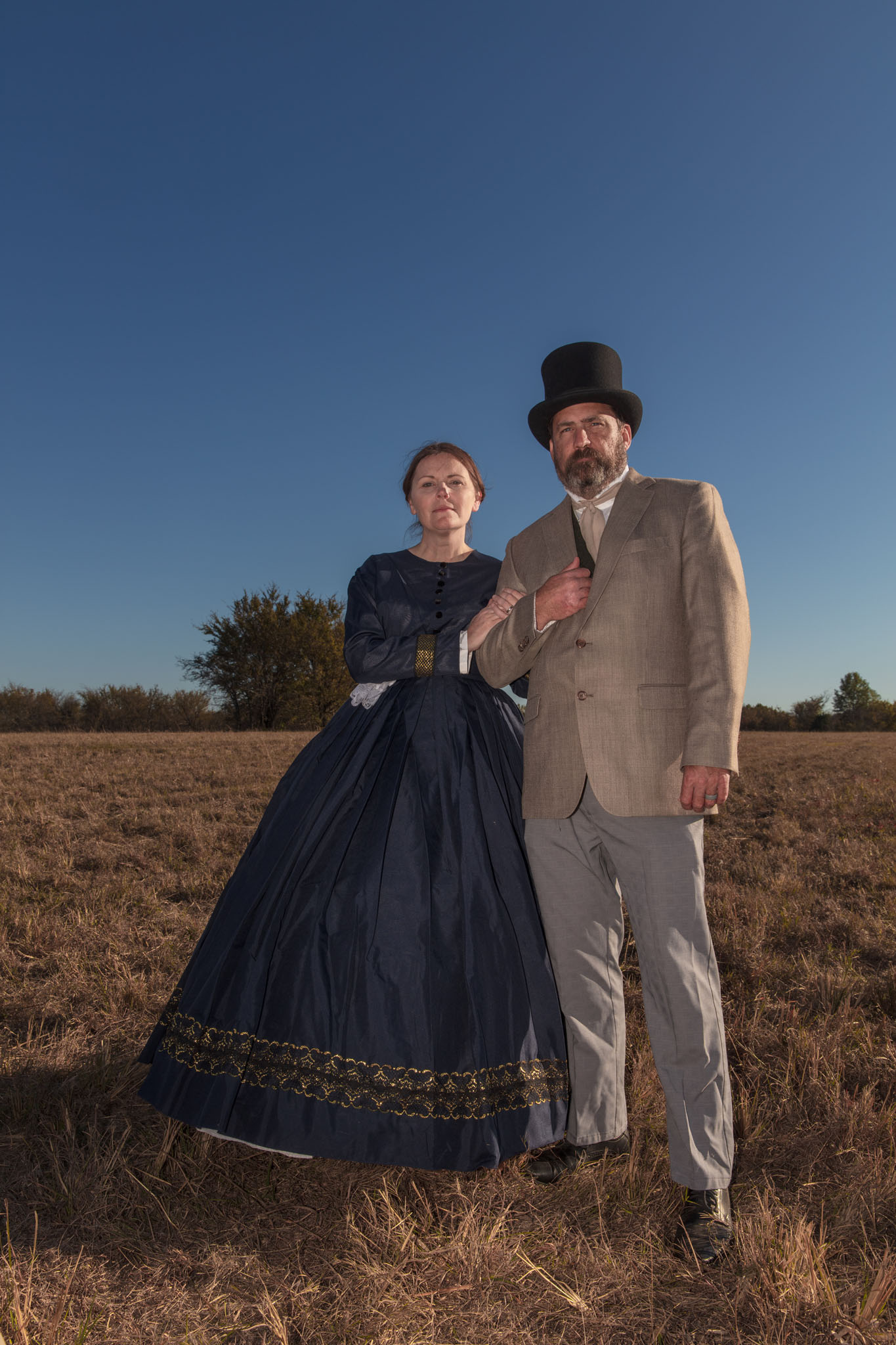Couple in 1860s dress standing on the prairie