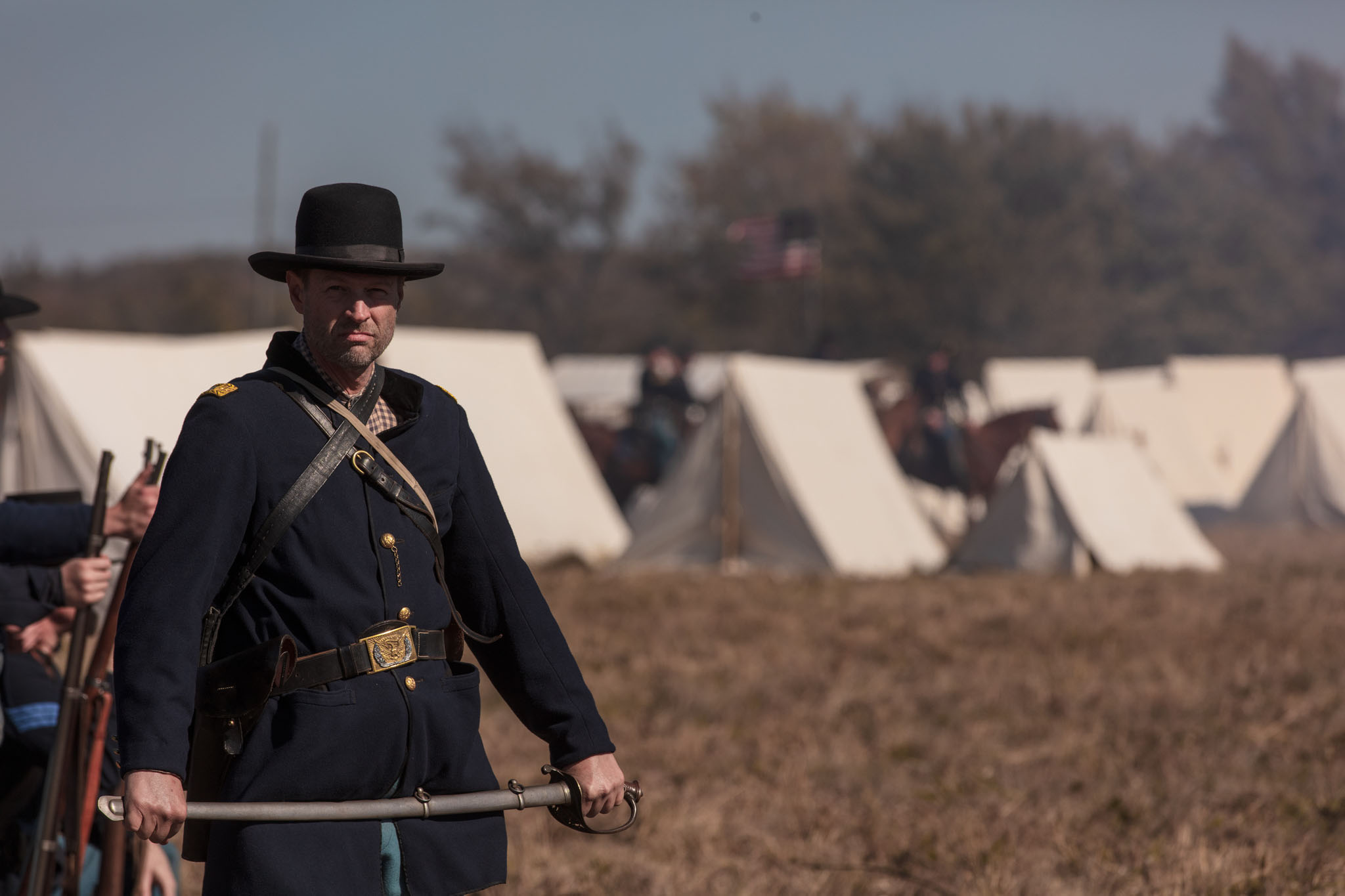 Union officer in a slouch hat in front of rows of white tents