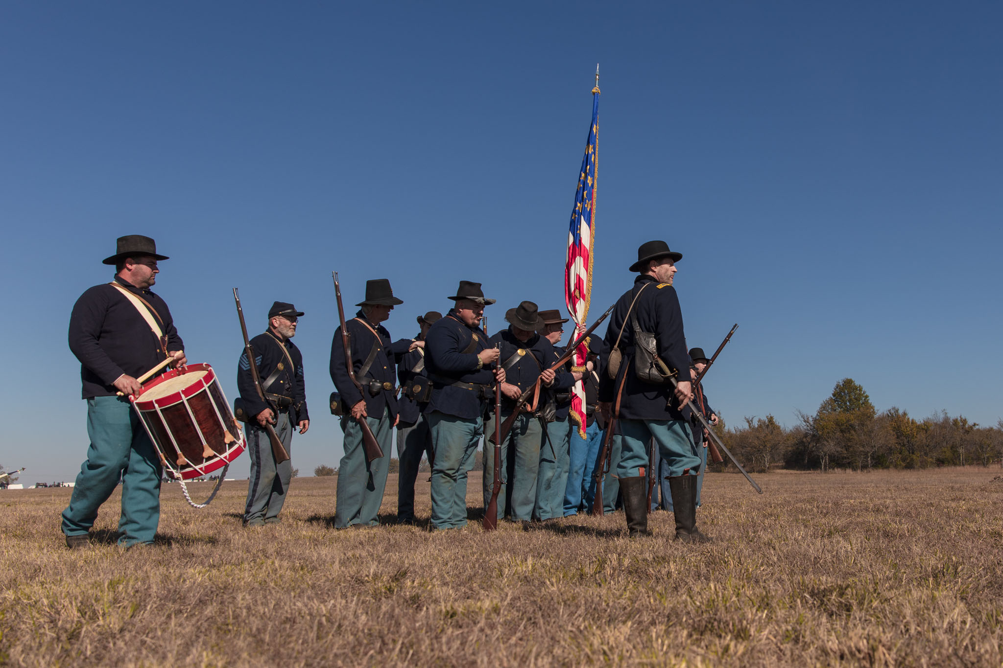 Union reenactors with a drummer and American flag lined up on the prairie