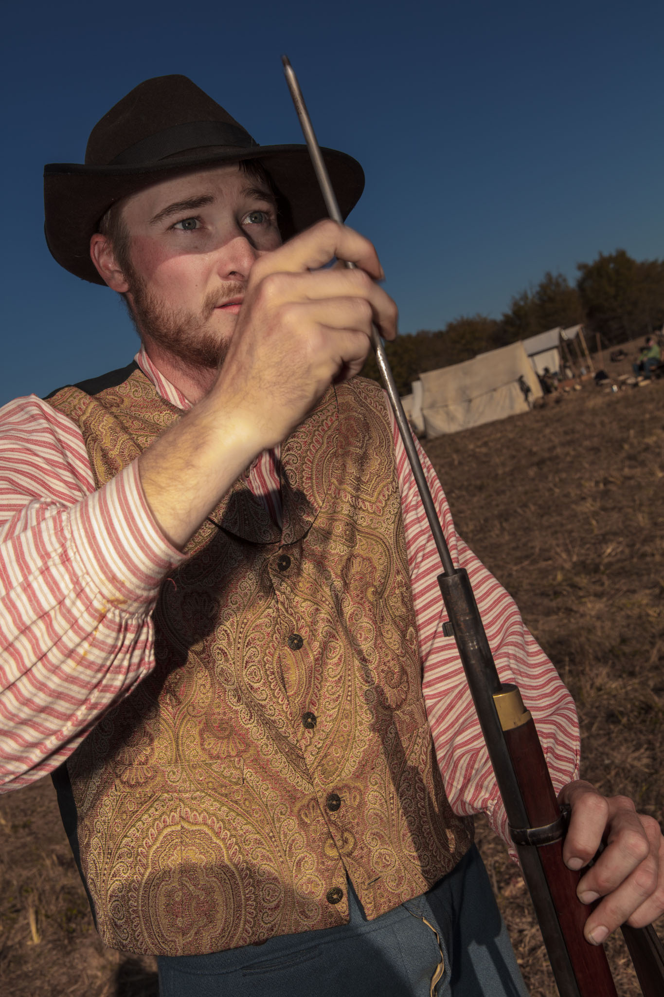 Reenactor in a slouch hat cleaning his rifle with a ramrod