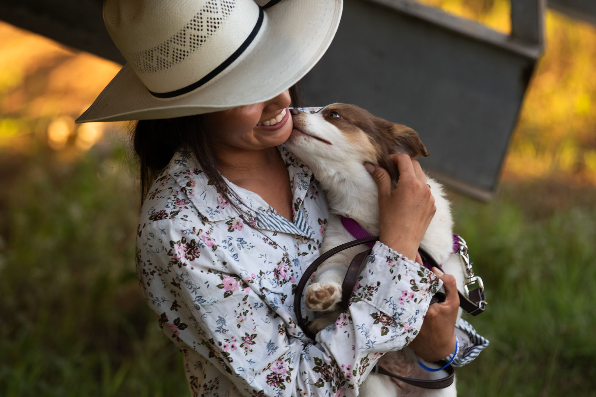 Young woman in a straw cowboy hat hugging her dog