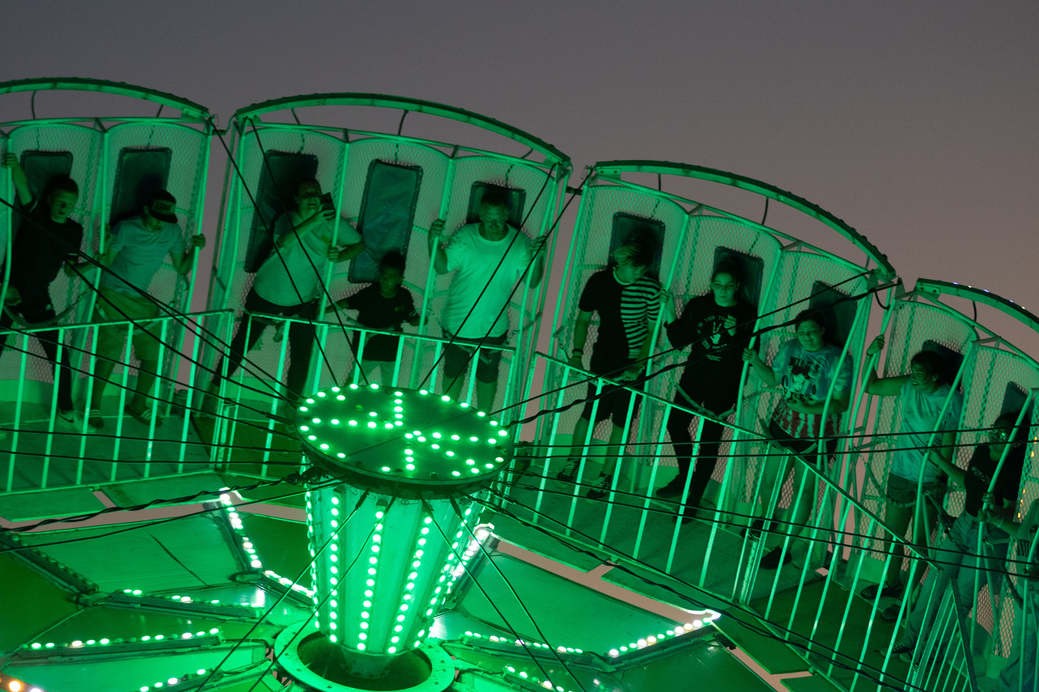 Carnival ride glowing green against the night sky