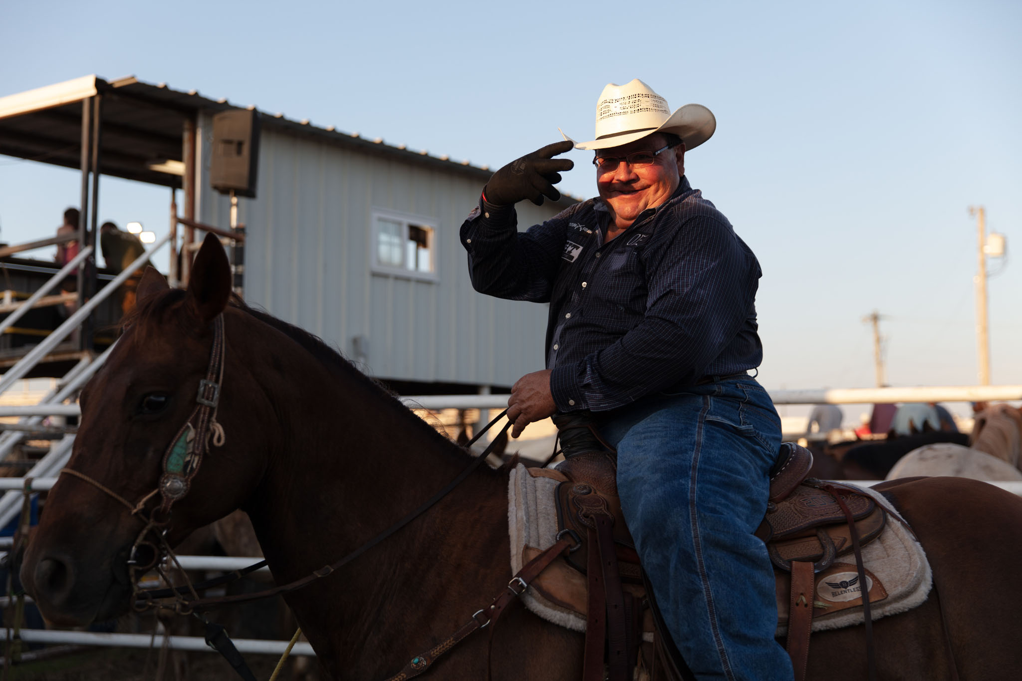 Cowboy on horseback shading his eyes at the rodeo arena