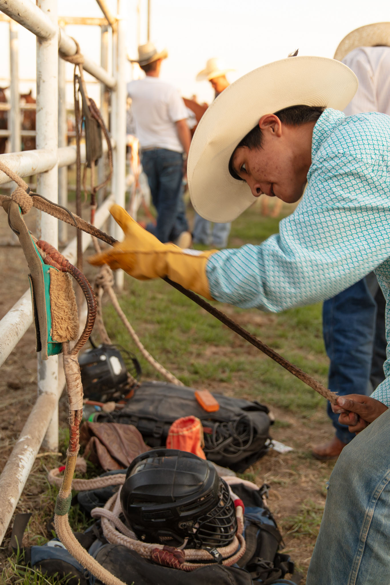 Cowboy adjusting his gear behind the chutes