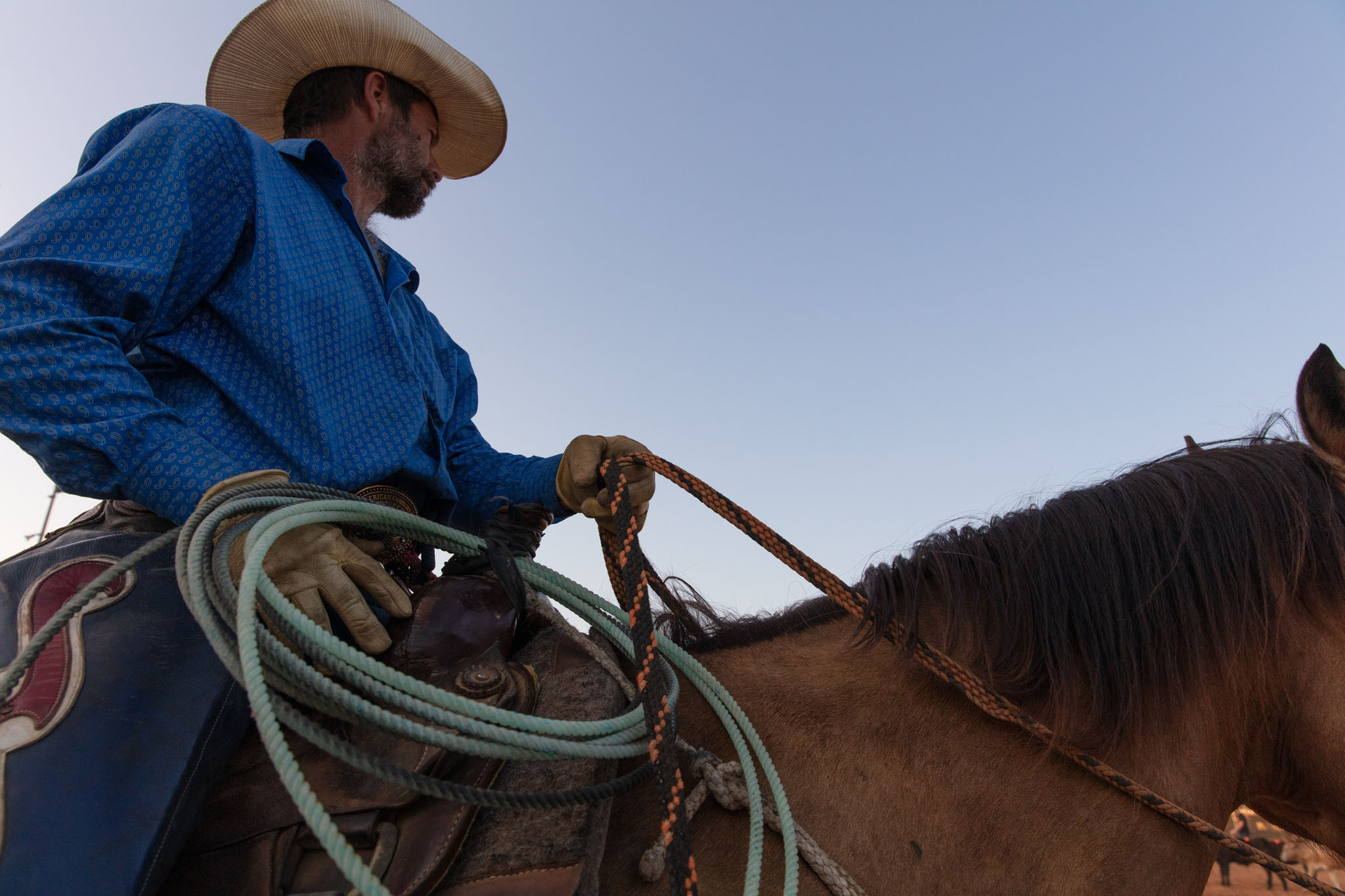 Roper on horseback coiling his rope