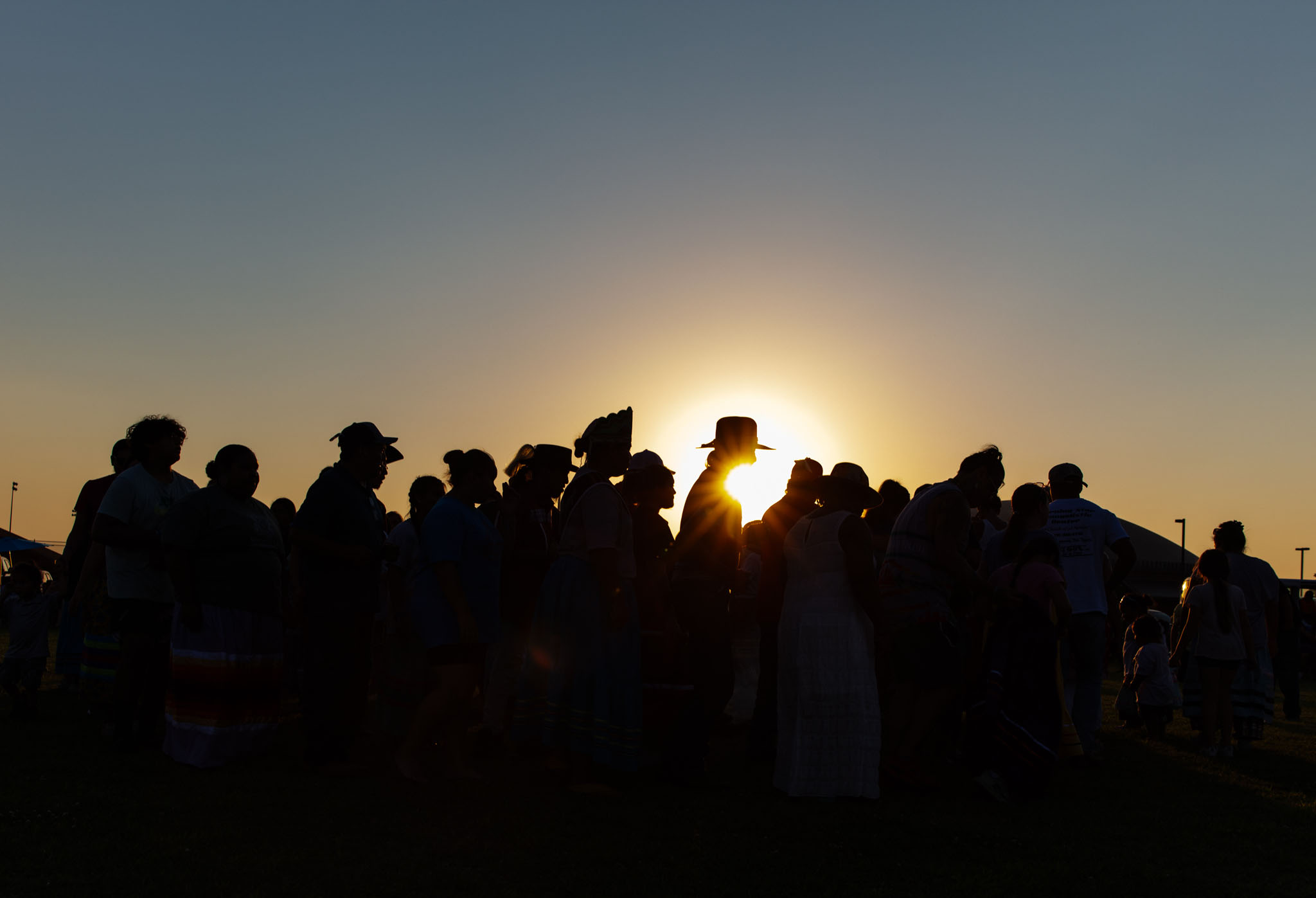 Festival crowd silhouetted against the setting sun at the Muscogee Nation Festival
