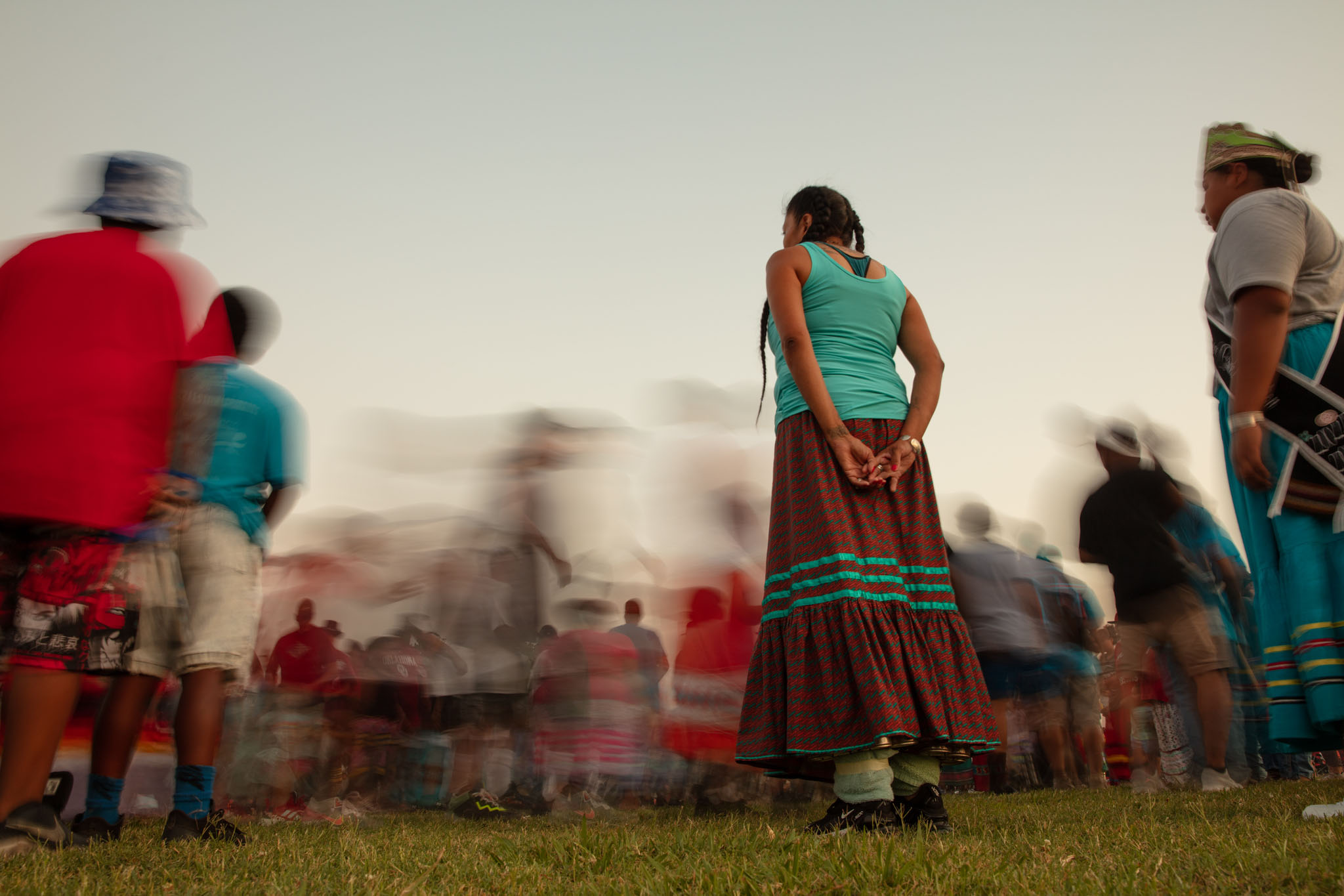 Women in traditional dress standing still as the crowd moves past in a blur