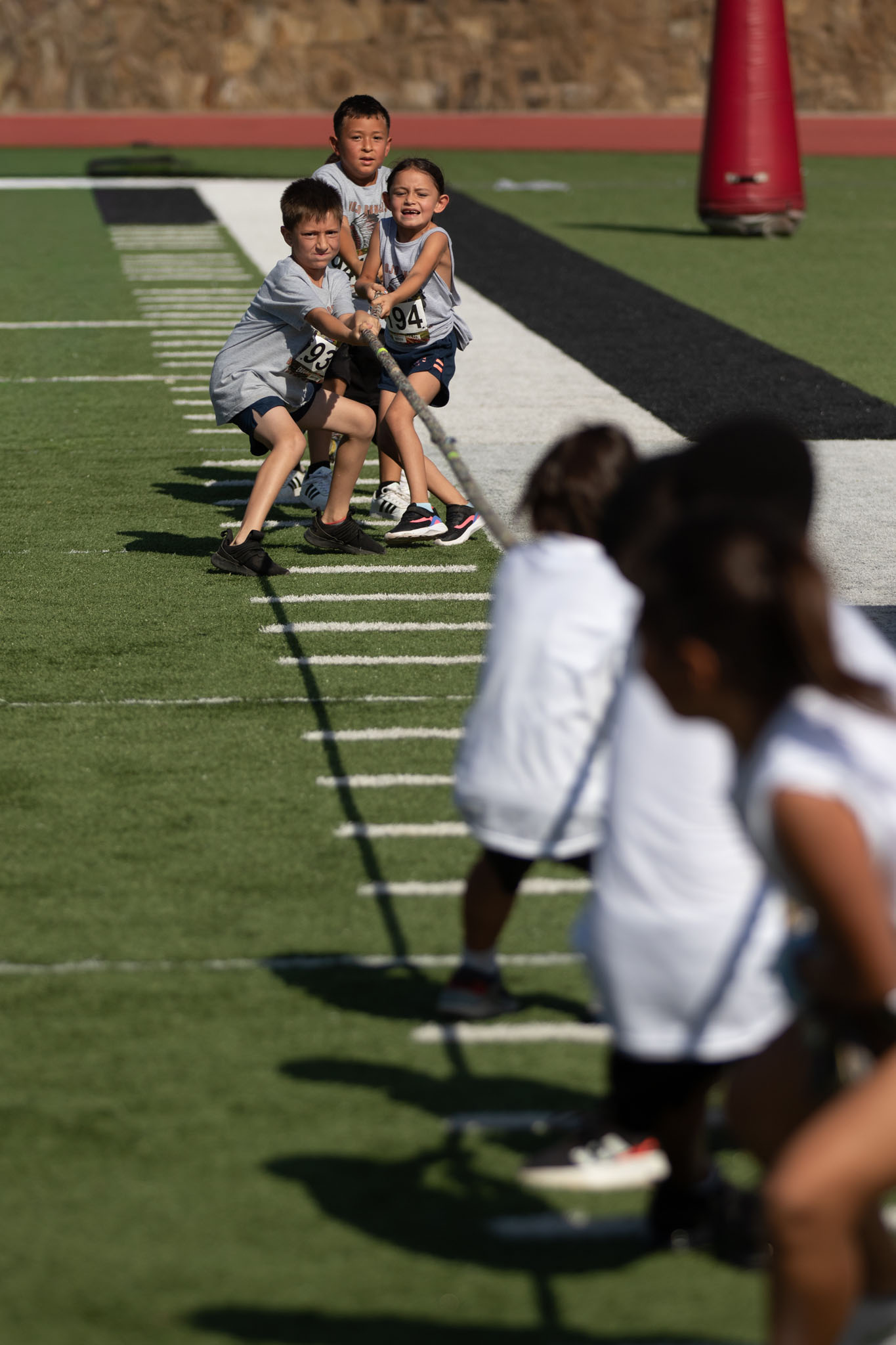 Children pulling in a tug-of-war on a football field