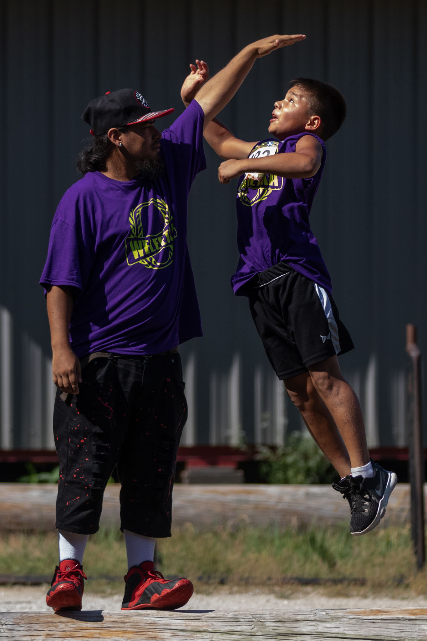 Boy leaping to high-five a man in a purple shirt