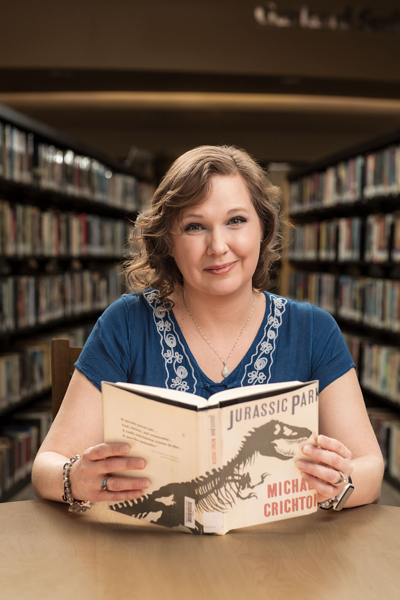 Woman seated at a library table holding an open book