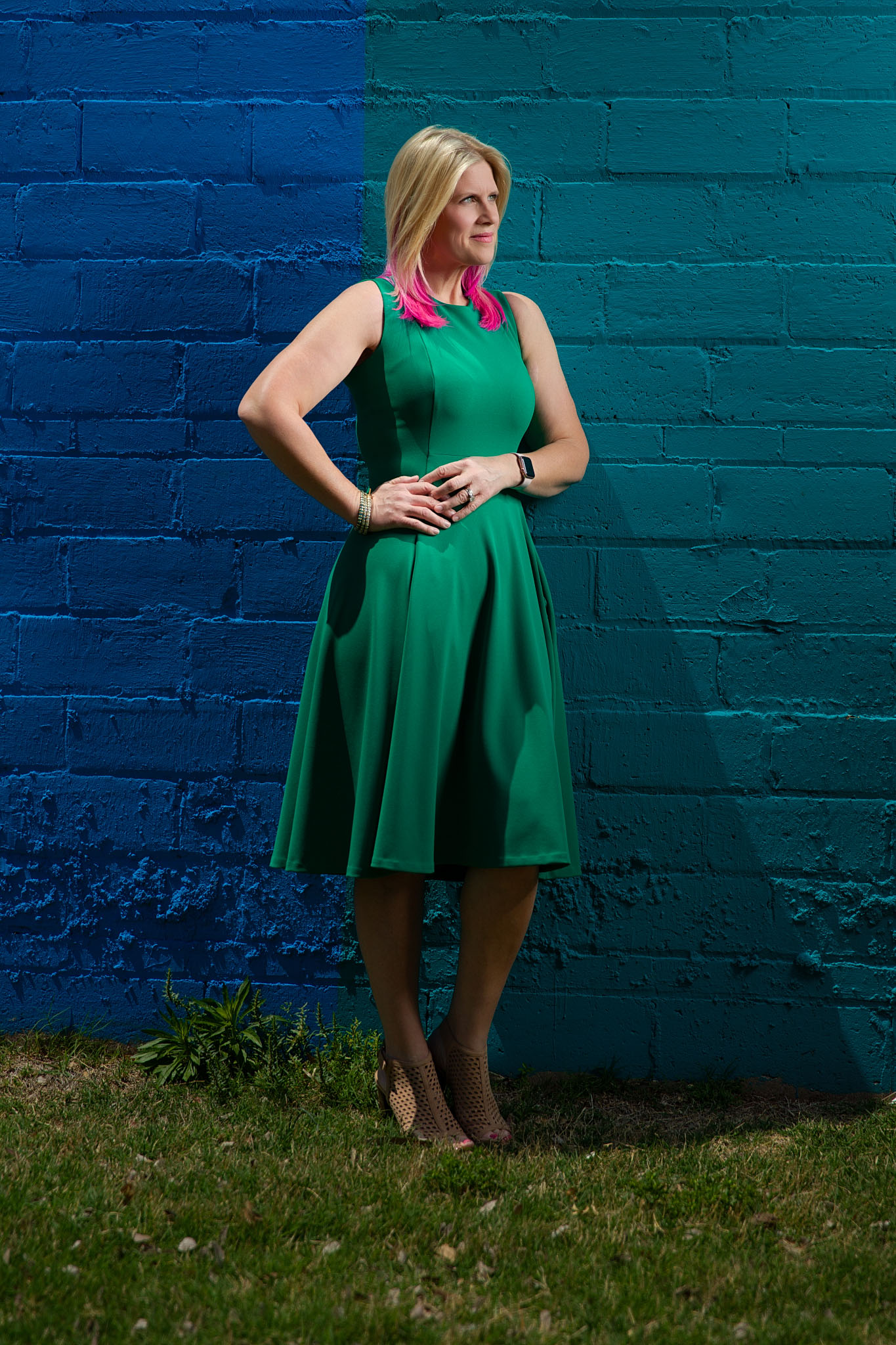 Woman in a green dress standing against a blue painted brick wall