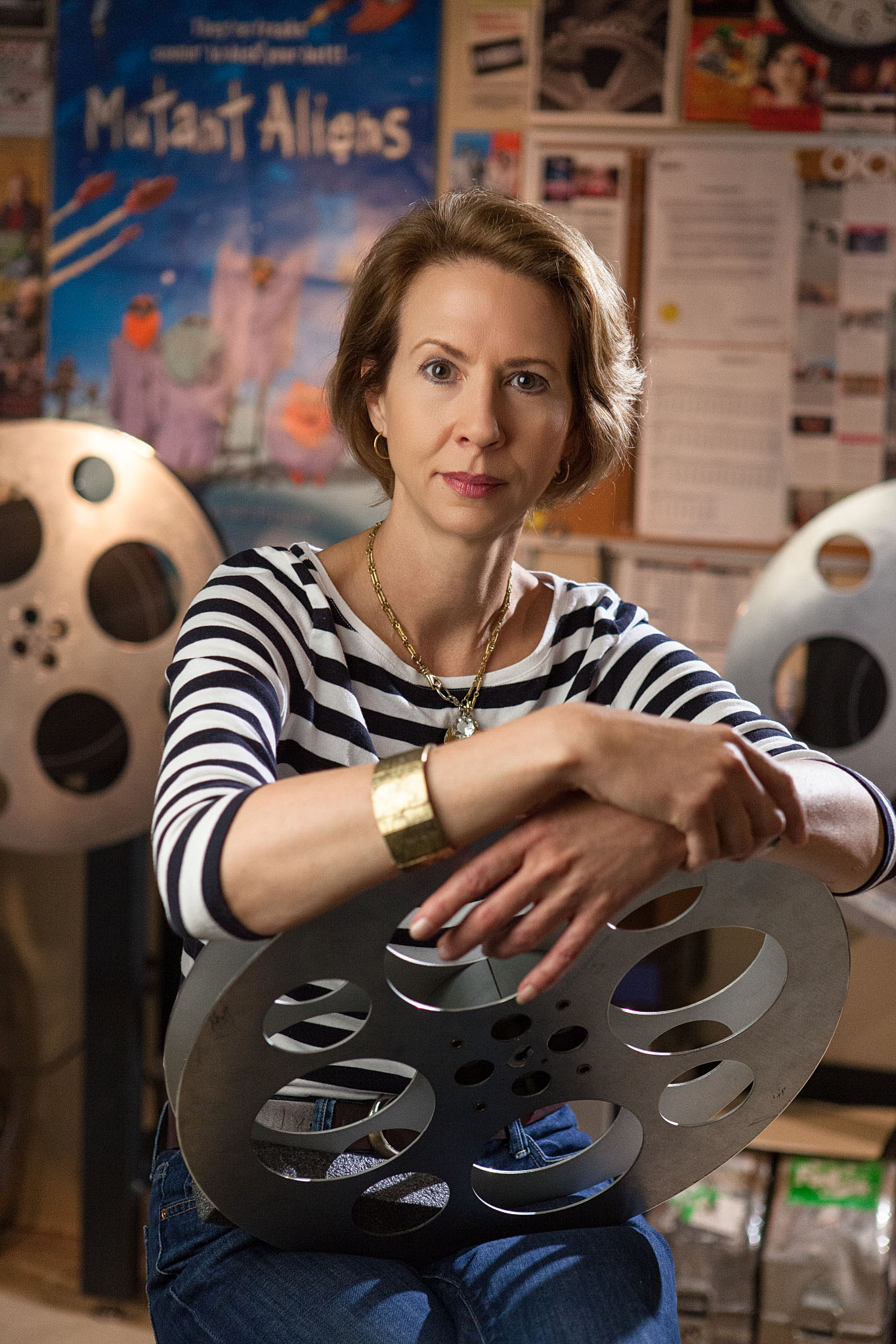 Woman holding a film reel in front of movie posters