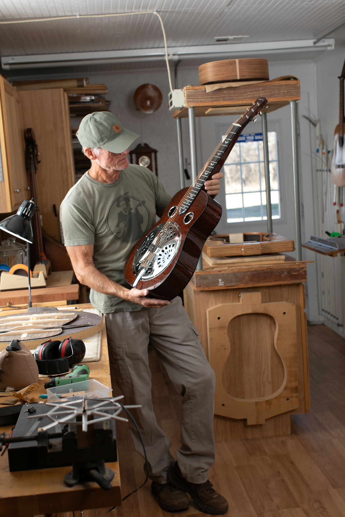 Luthier holding a resonator guitar in his woodworking shop