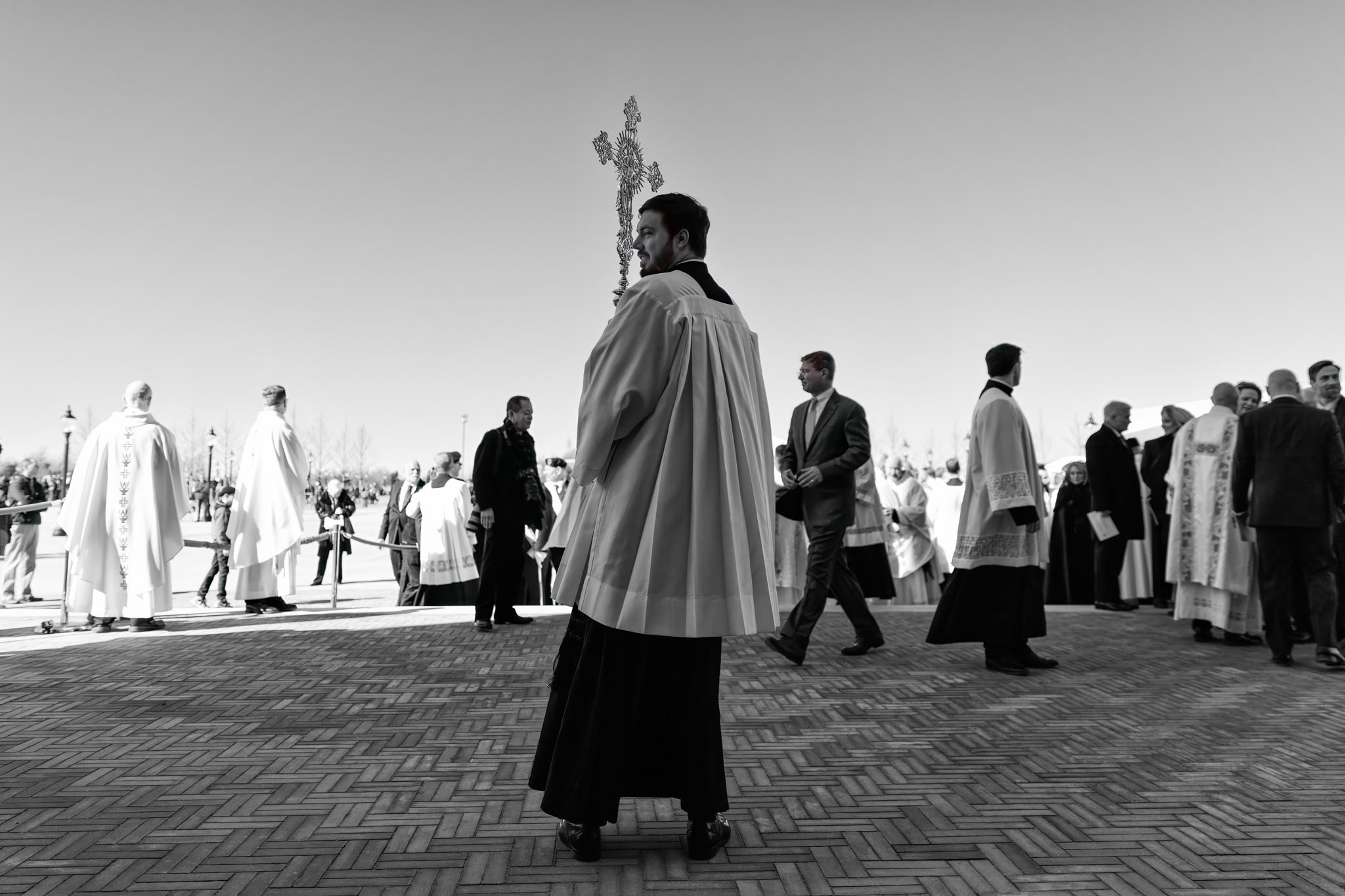 Priest walking across the plaza toward the shrine as clergy gather
