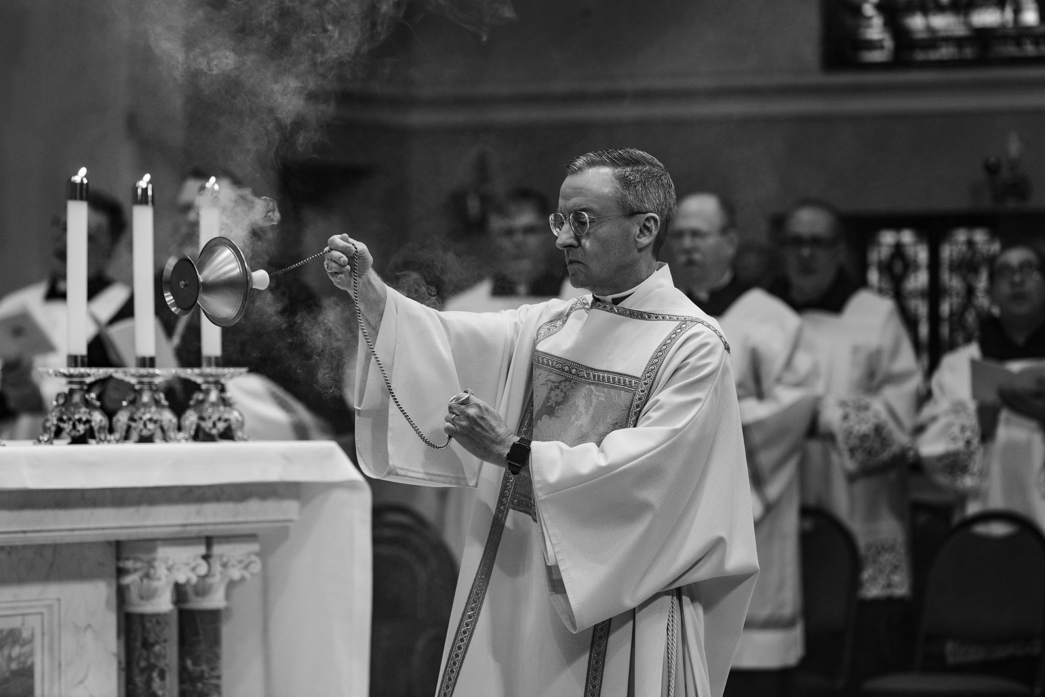 Priests concelebrating at the altar with raised hands
