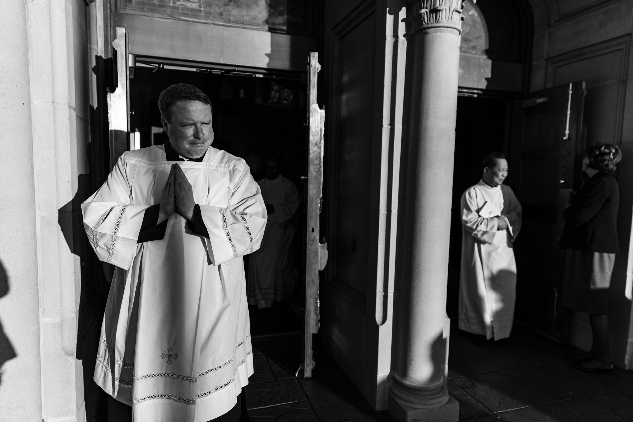Priest standing with hands folded in a doorway of the cathedral